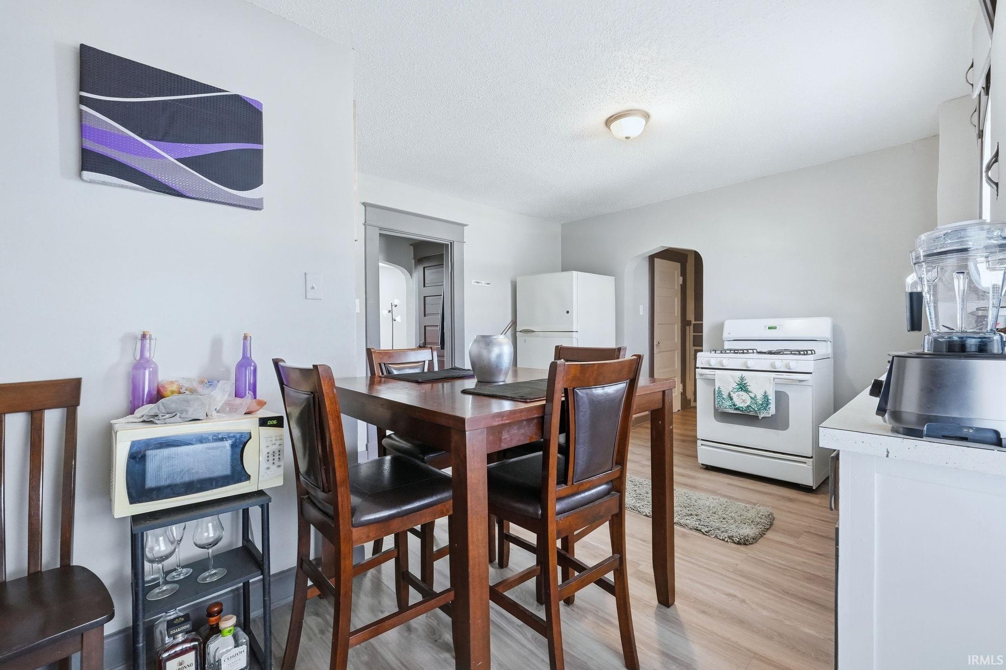 Dining room with arched walkways and light wood-style floors