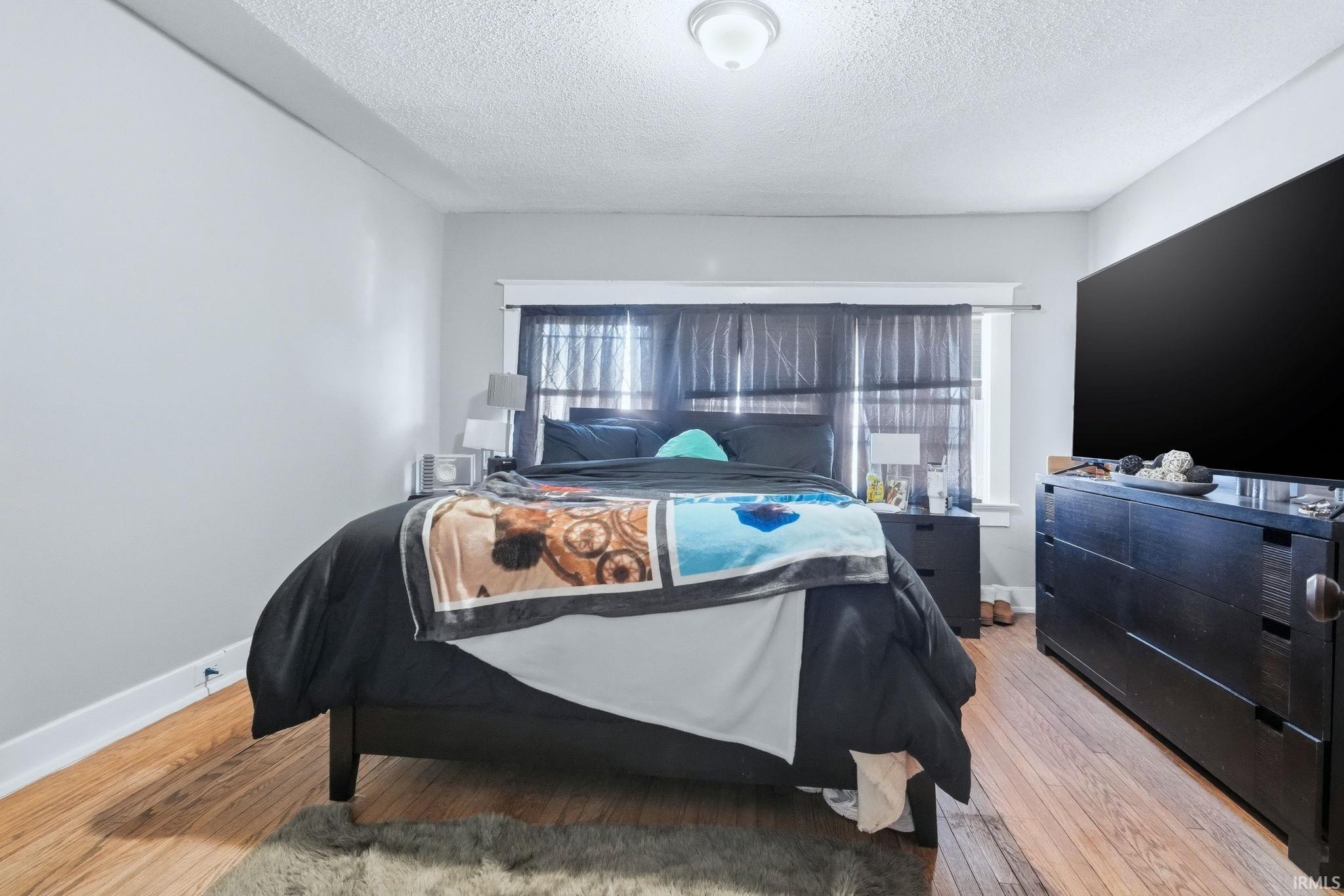 Bedroom with light wood-style flooring and a textured ceiling