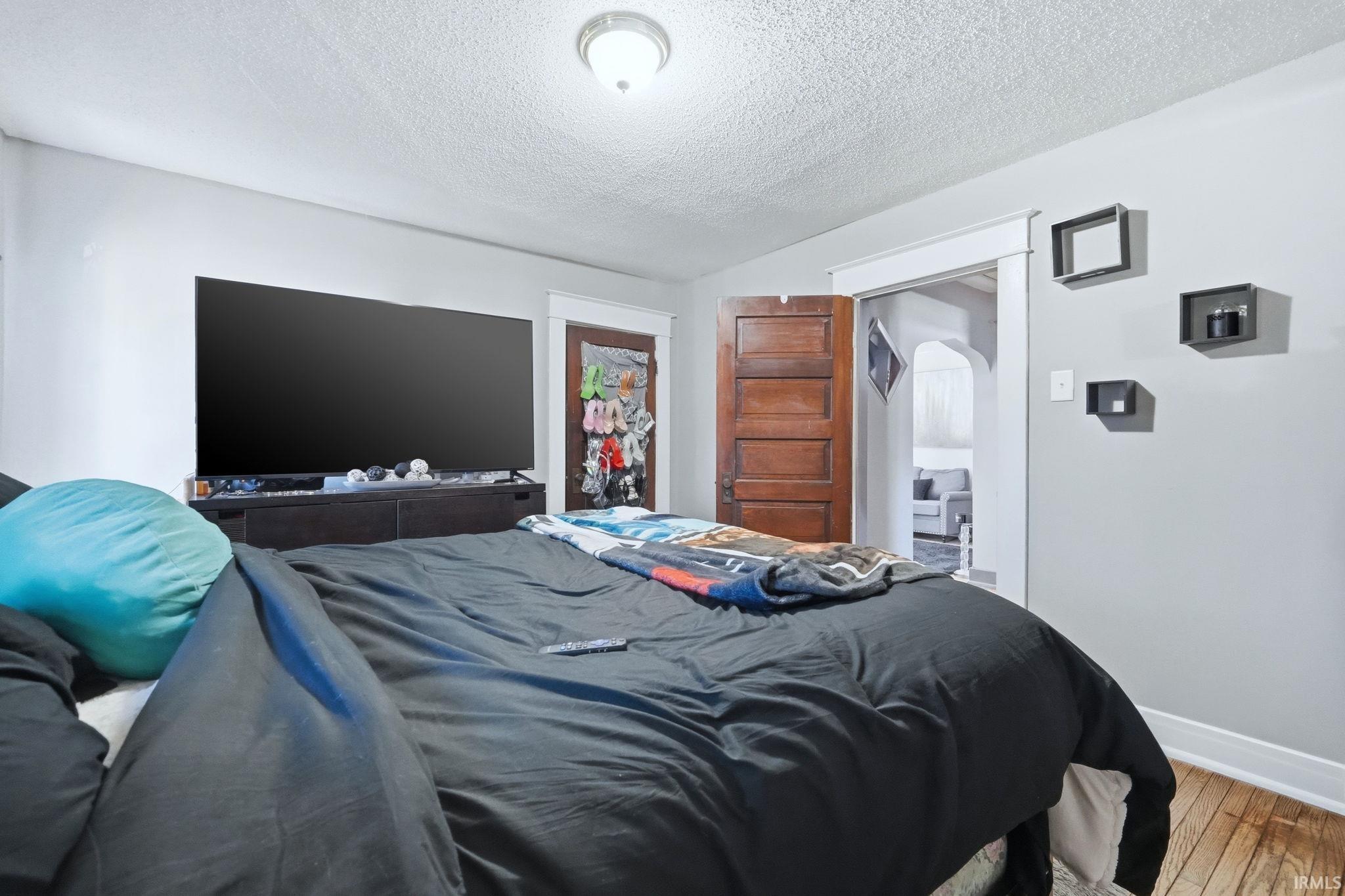 Bedroom featuring hardwood / wood-style floors, a textured ceiling, and a closet