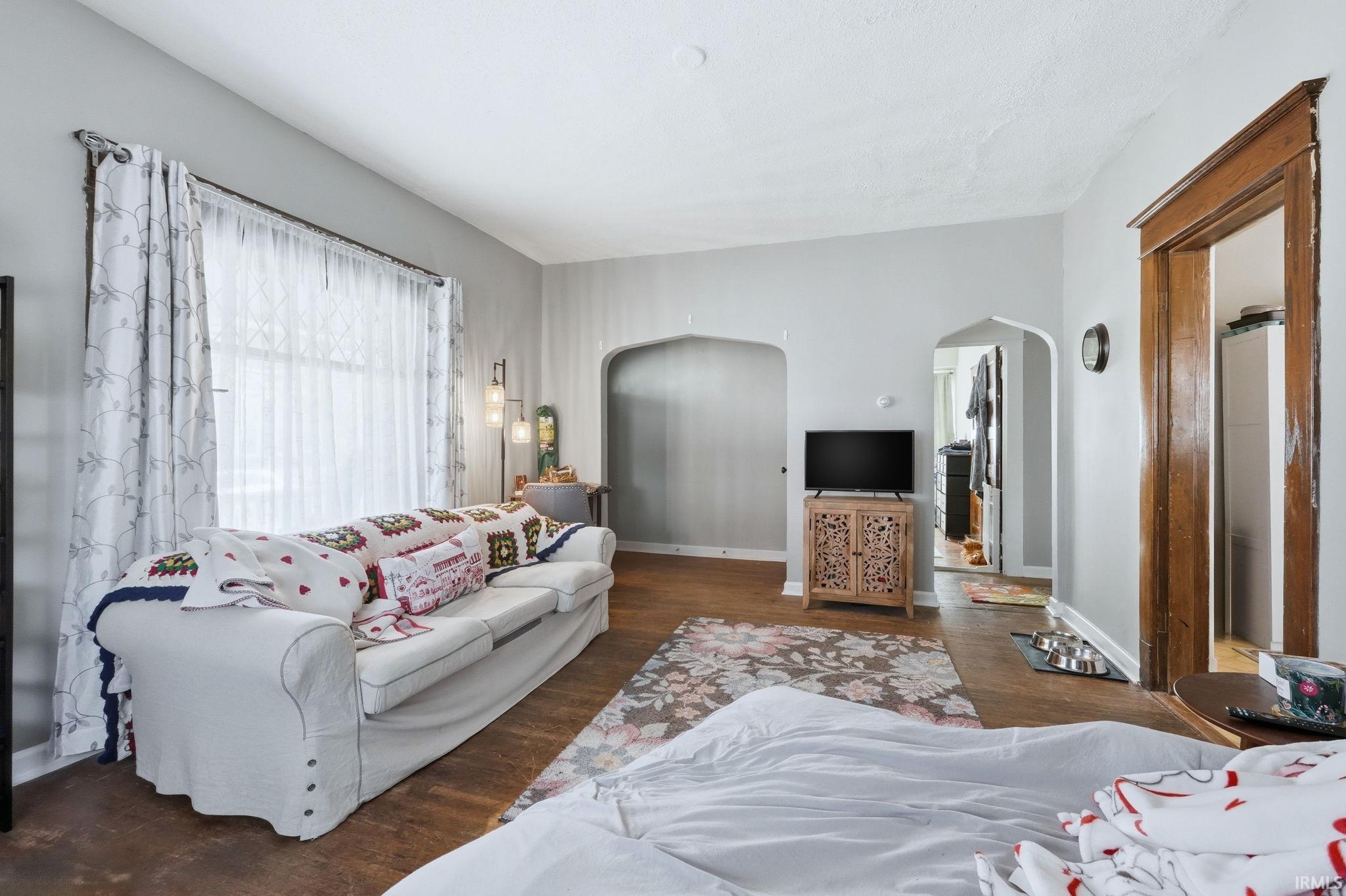 Living room featuring dark wood-style floors and arched walkways