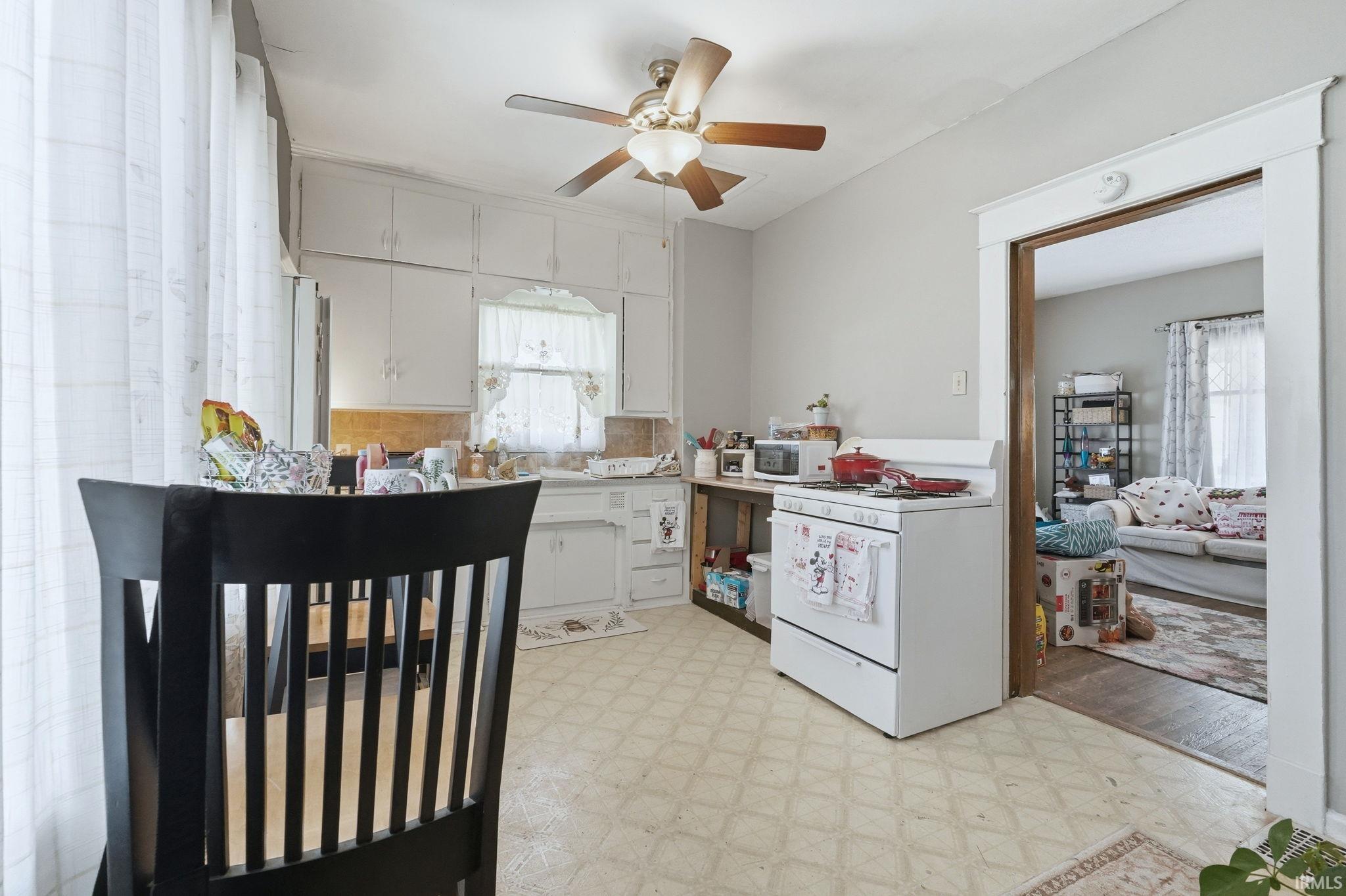 Kitchen featuring light floors, white appliances, a ceiling fan, white cabinetry, and light countertops