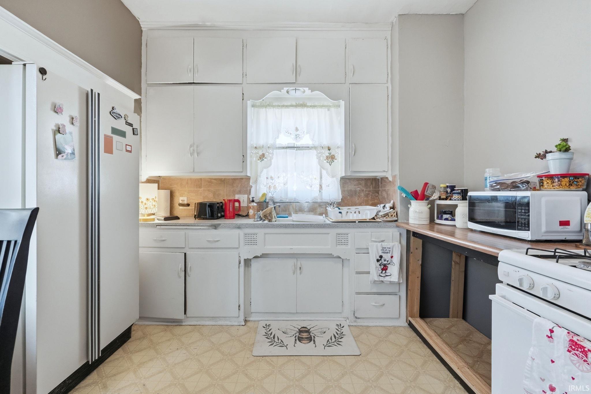 Kitchen featuring light floors, white appliances, and light countertops