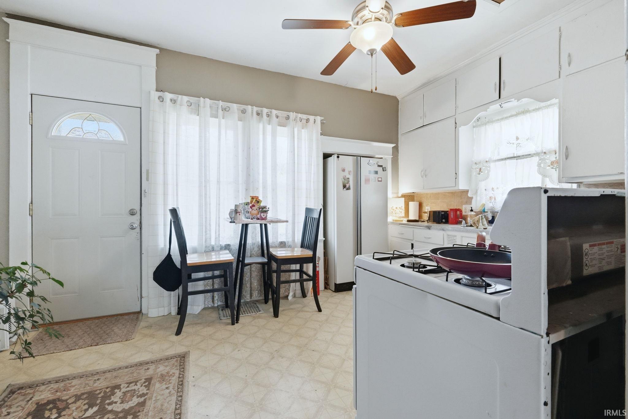 Kitchen with white cabinets, light flooring, white appliances, light countertops, and ceiling fan