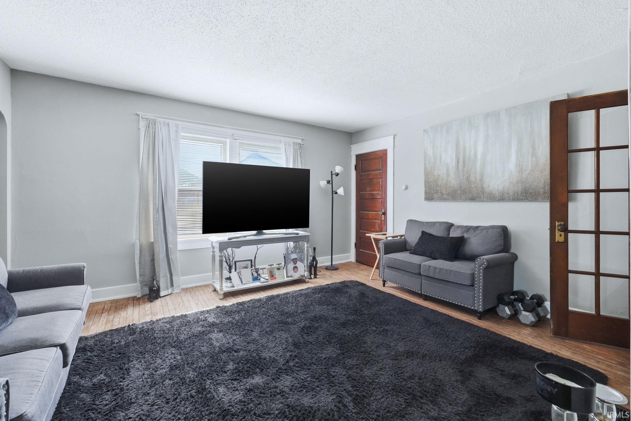 Living area with light wood finished floors and a textured ceiling