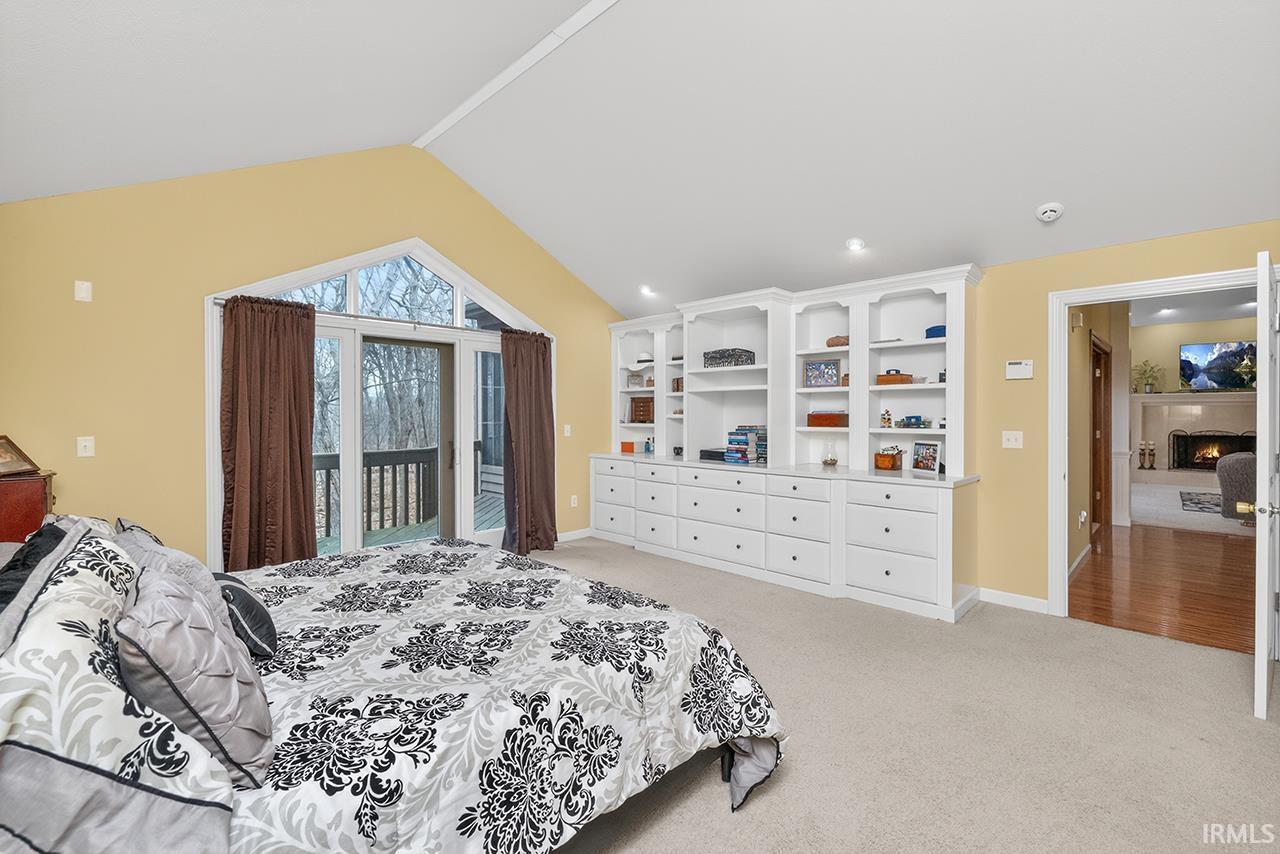 Bedroom with light colored carpet, a warm lit fireplace, access to outside, and recessed lighting
