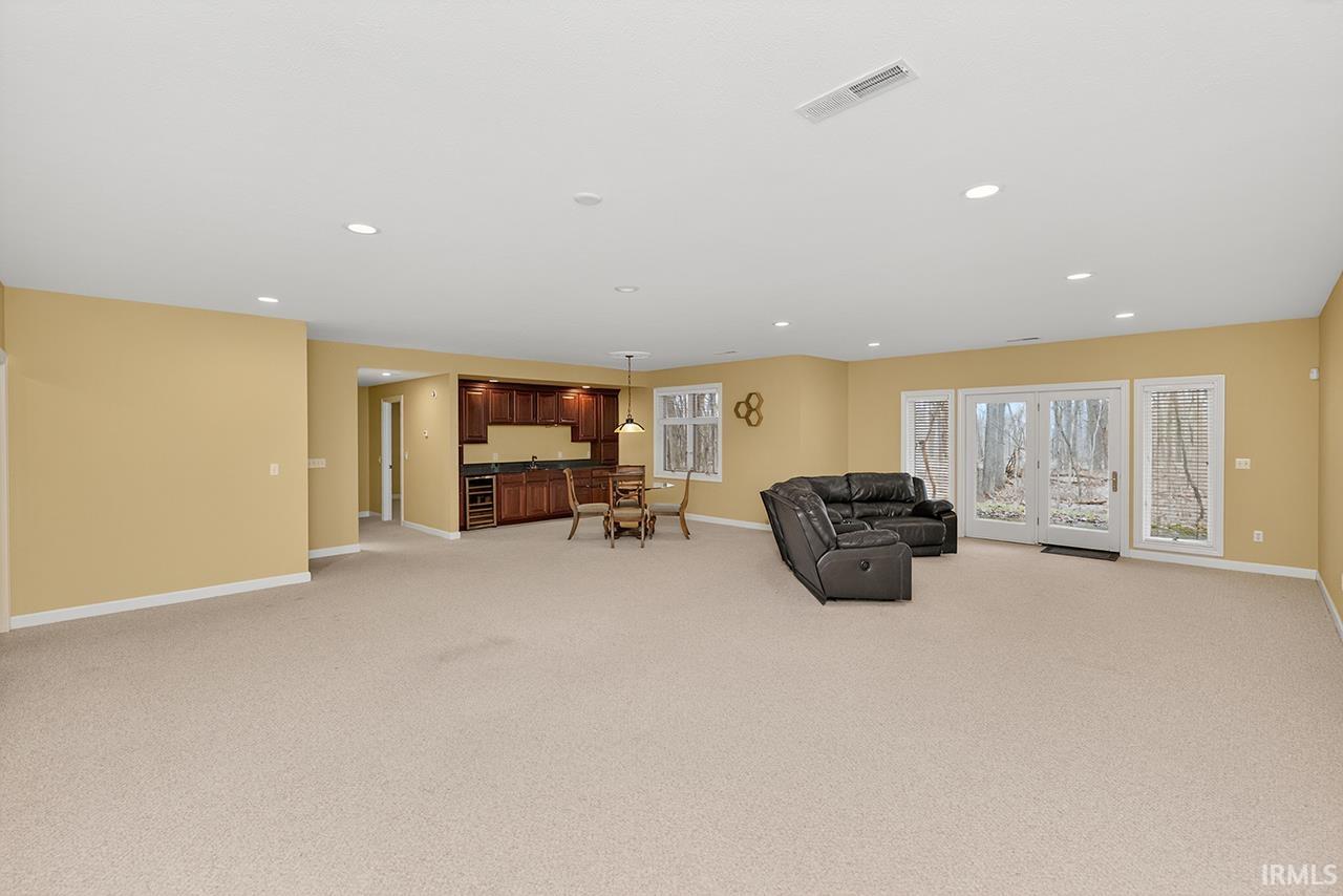 Living room featuring light colored carpet, recessed lighting, and beverage cooler