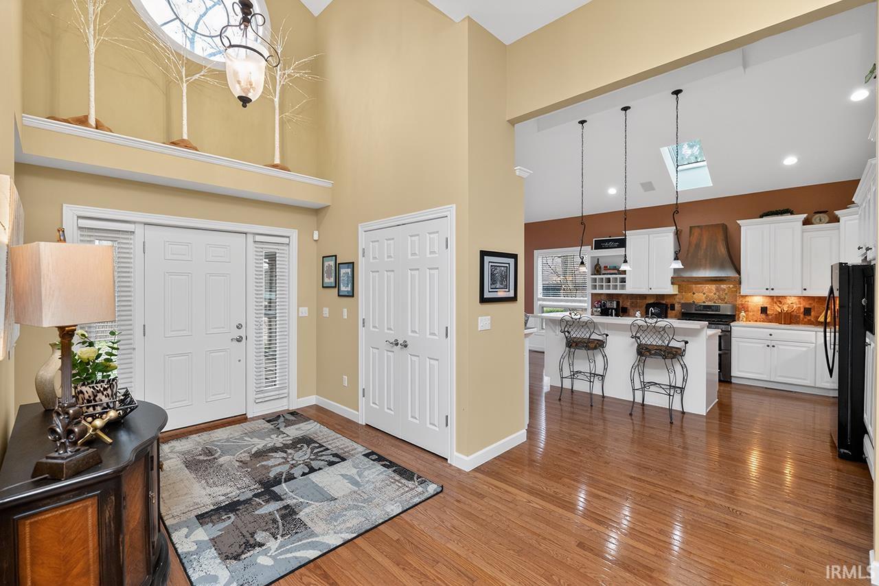 Foyer entrance with a skylight, dark wood finished floors, and a high ceiling