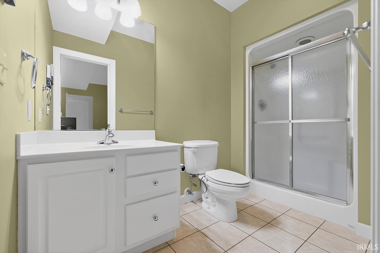 Full bath featuring vanity, a stall shower, and light tile patterned floors