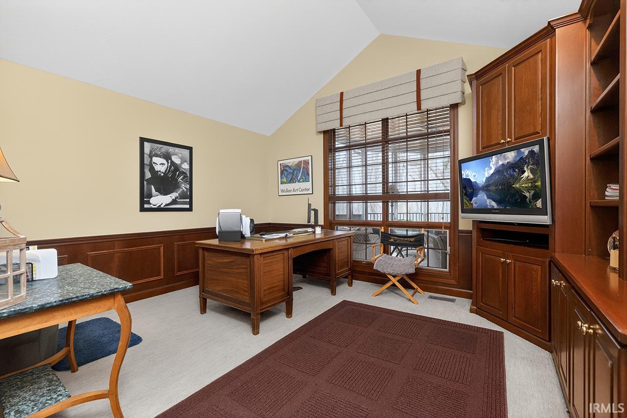 Home office with lofted ceiling and wainscoting