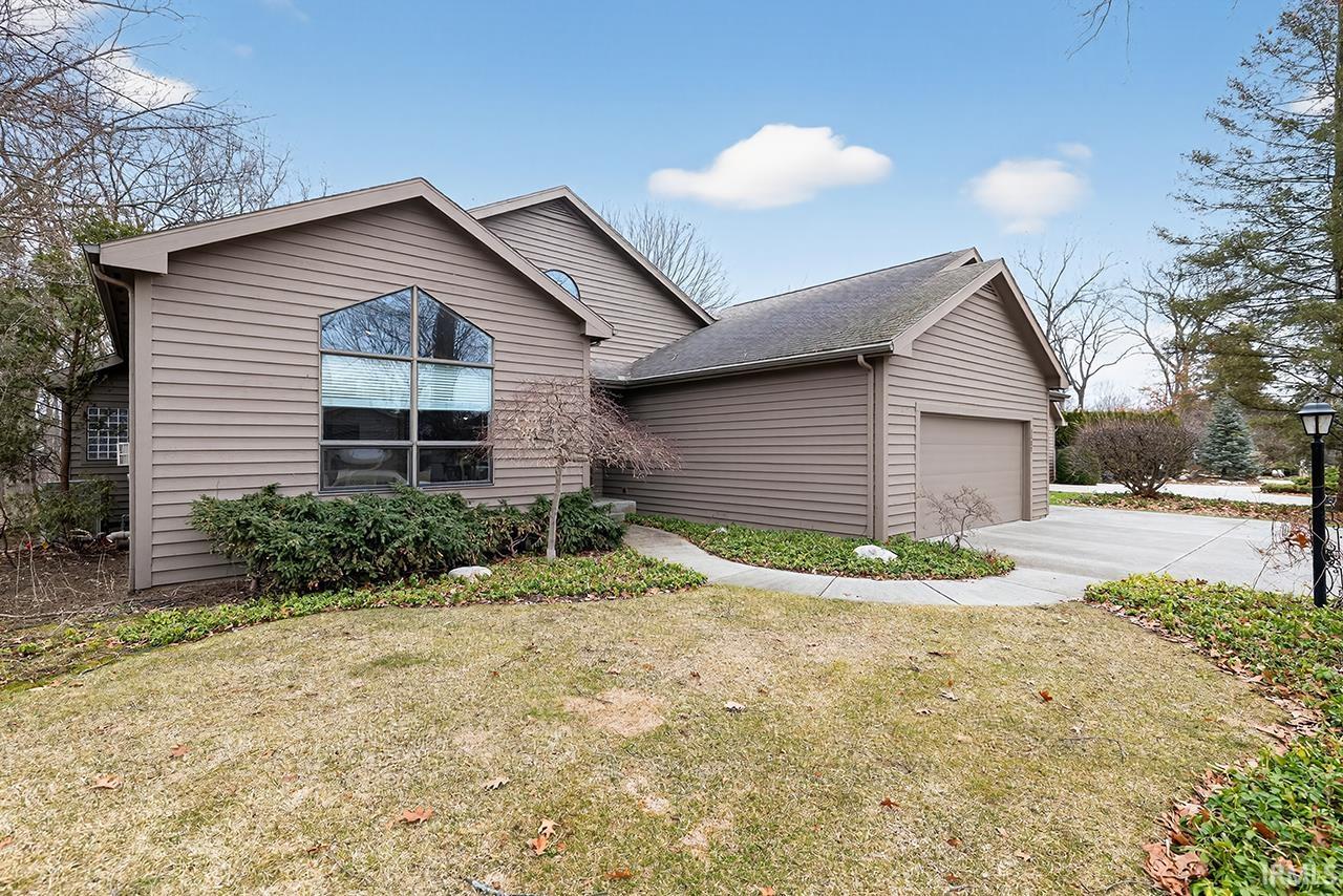 View of front of property with a front yard, an attached garage, concrete driveway, and roof with shingles