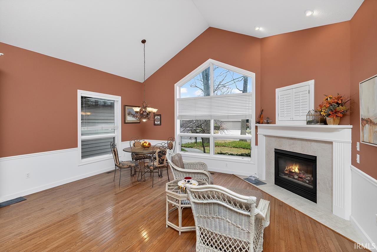 Living area with light wood-style flooring, a tiled fireplace, lofted ceiling, and hanging lights