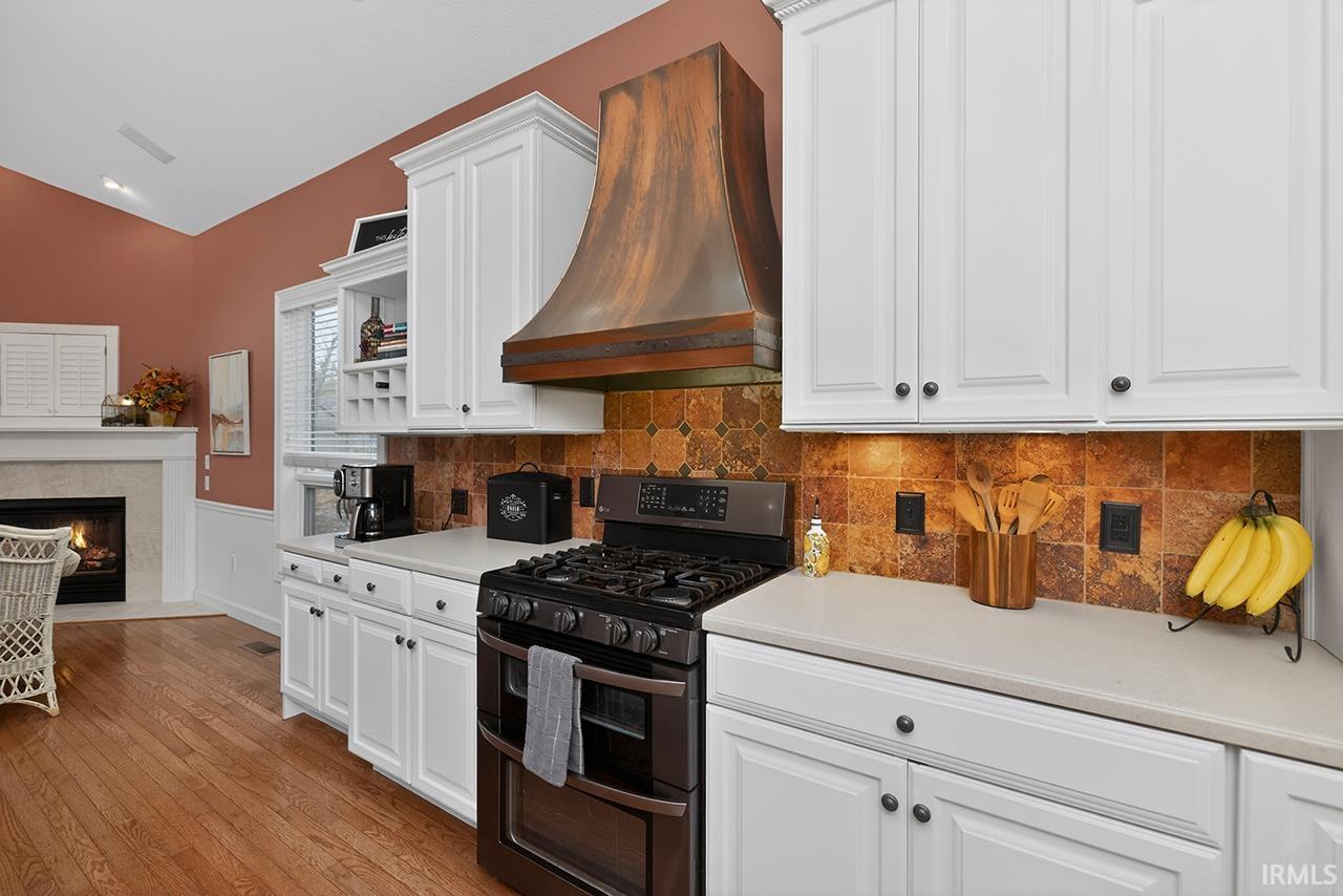 Kitchen with white cabinetry, range with two ovens, light countertops, vaulted ceiling, and wainscoting