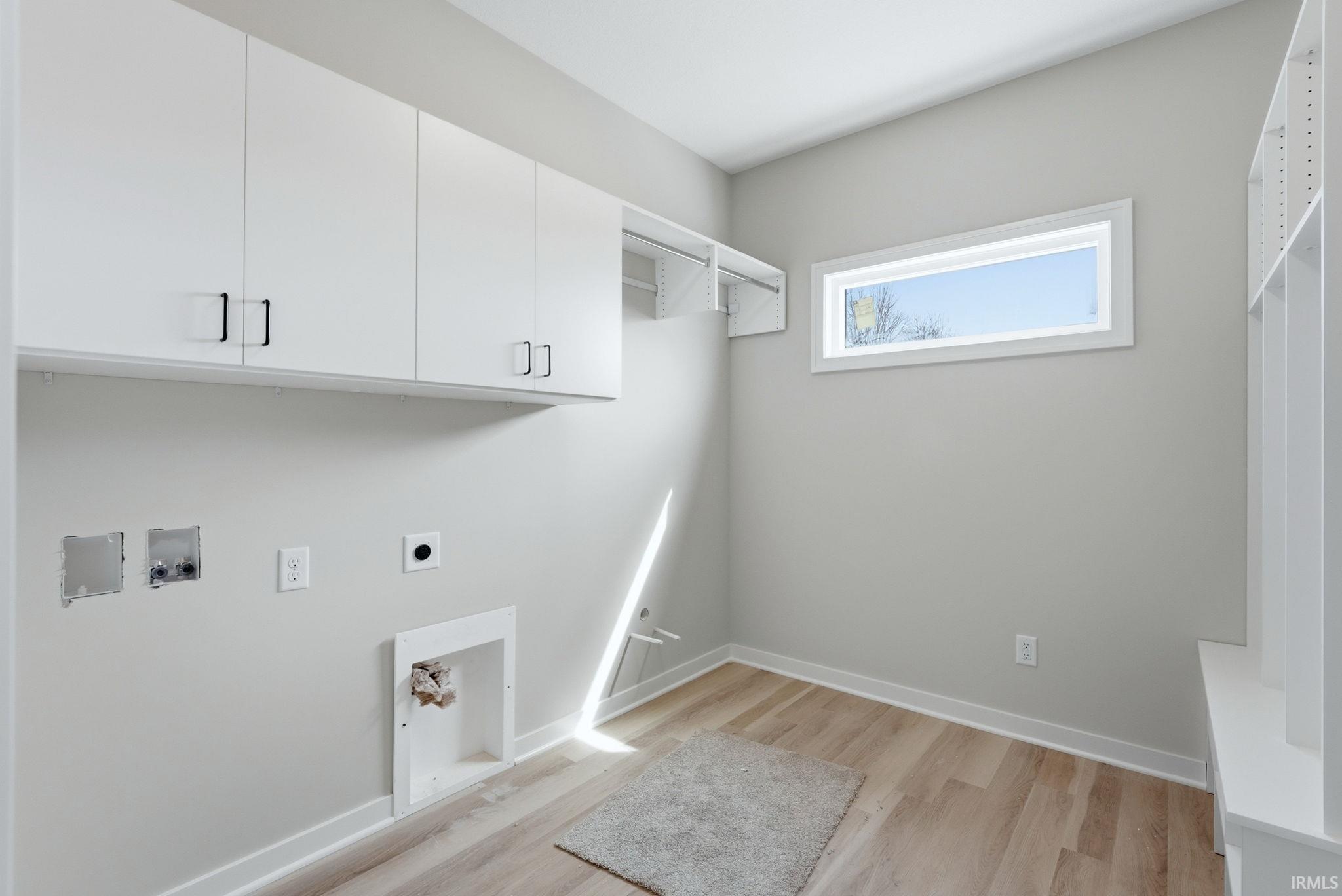 Laundry area with cabinet space, light wood-style flooring, hookup for a washing machine, and electric dryer hookup