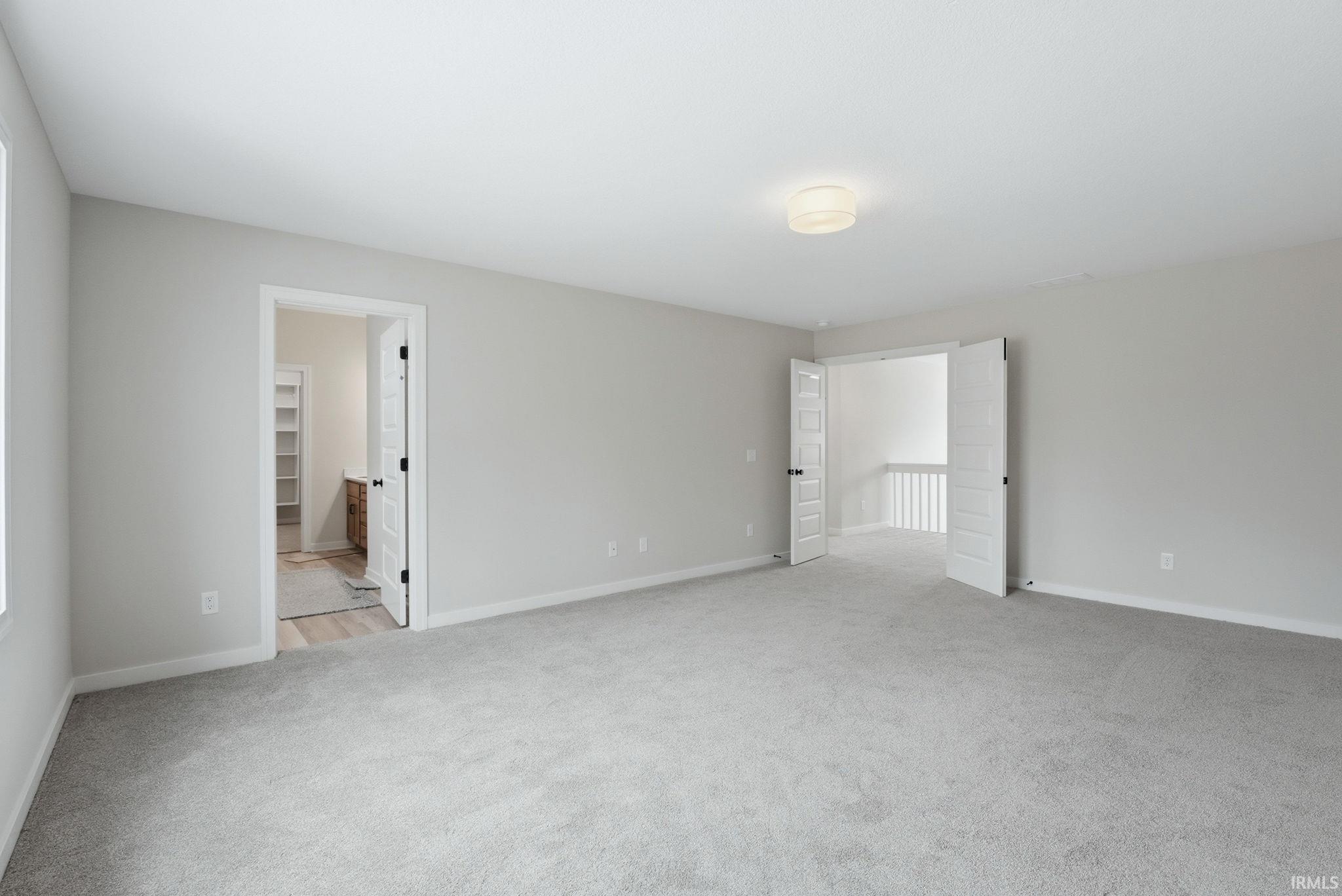 Unfurnished bedroom featuring light colored carpet and ensuite bathroom