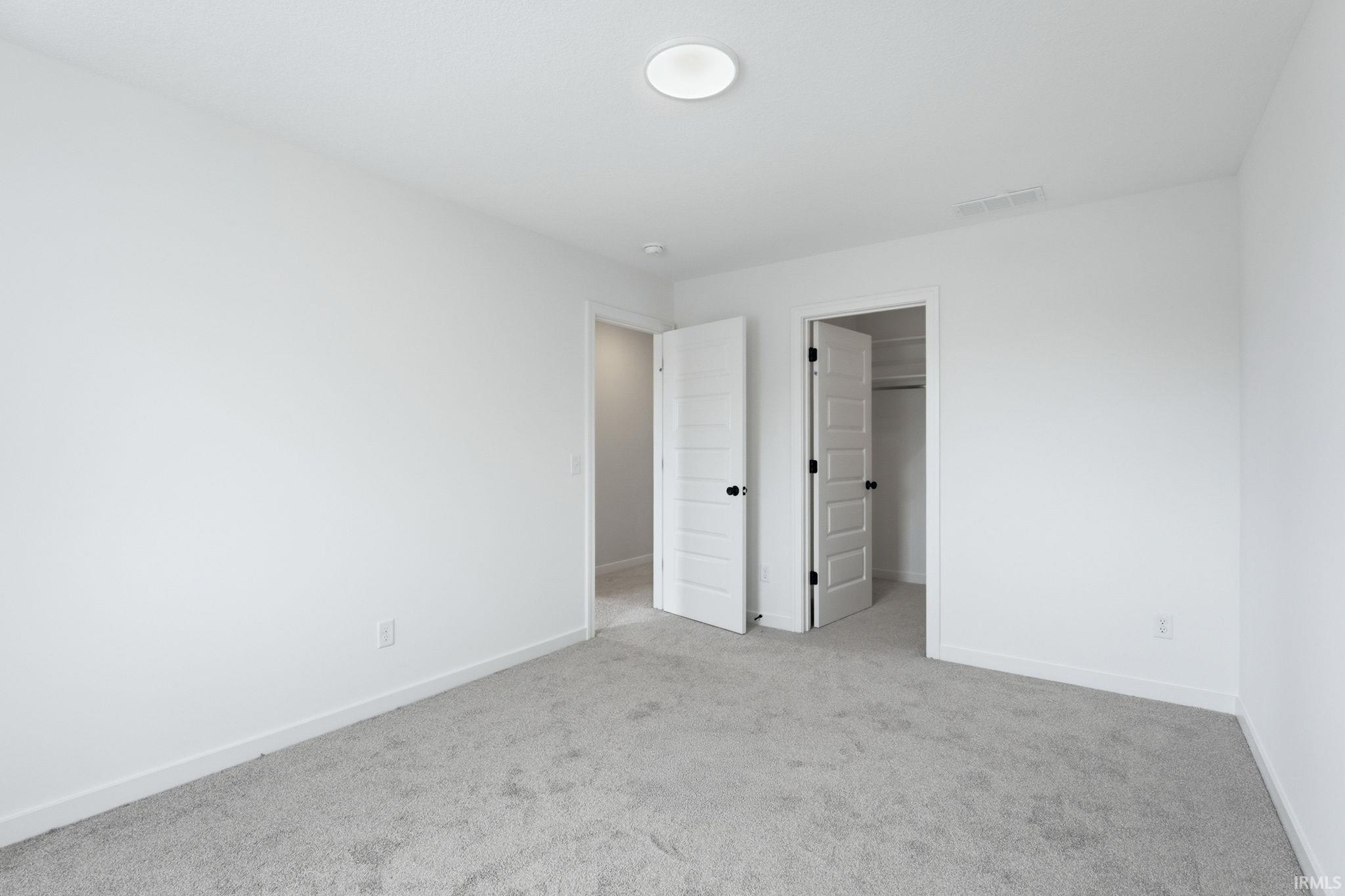Unfurnished bedroom with a walk in closet and light colored carpet