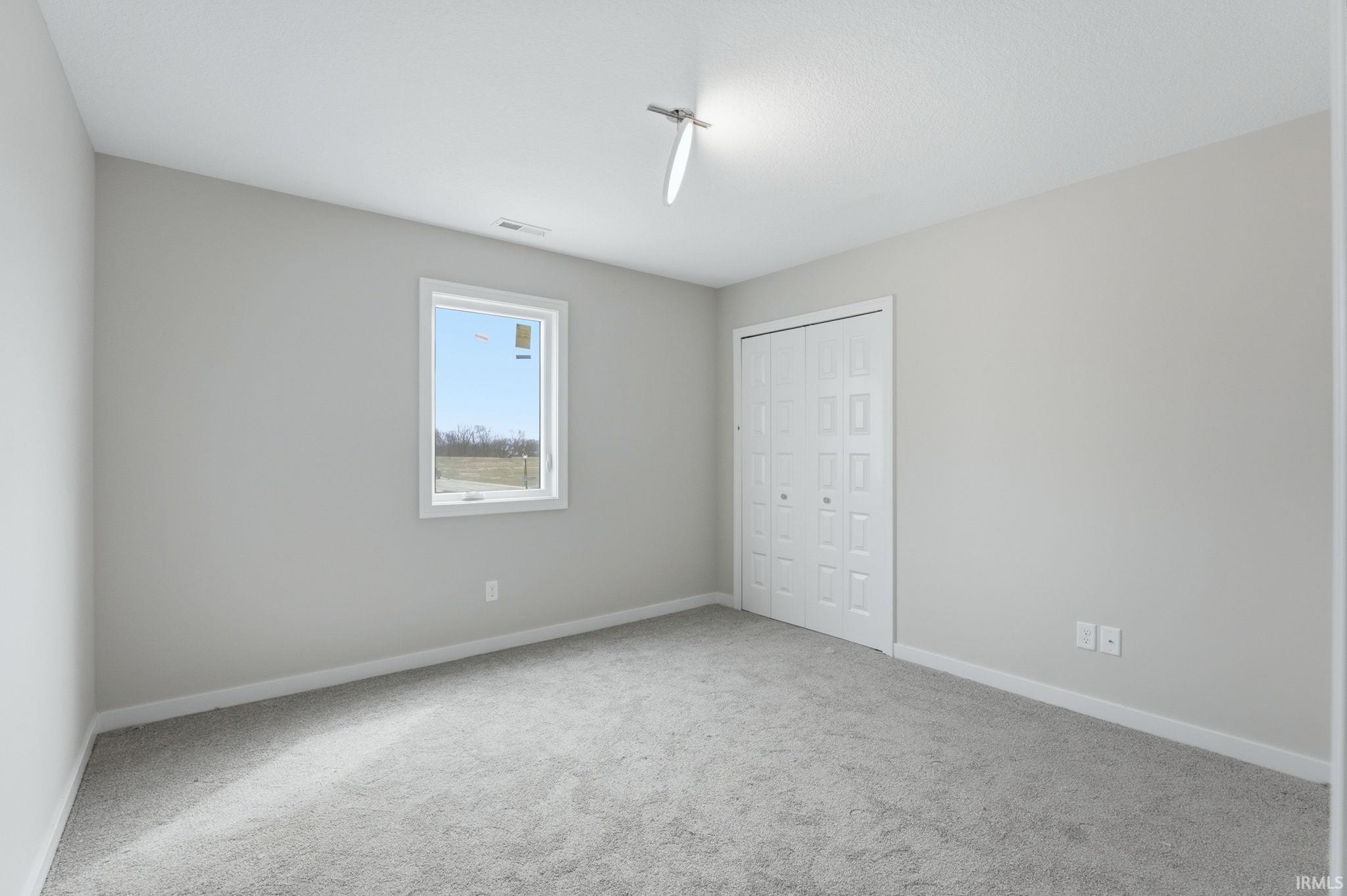 Unfurnished bedroom with light carpet and a closet