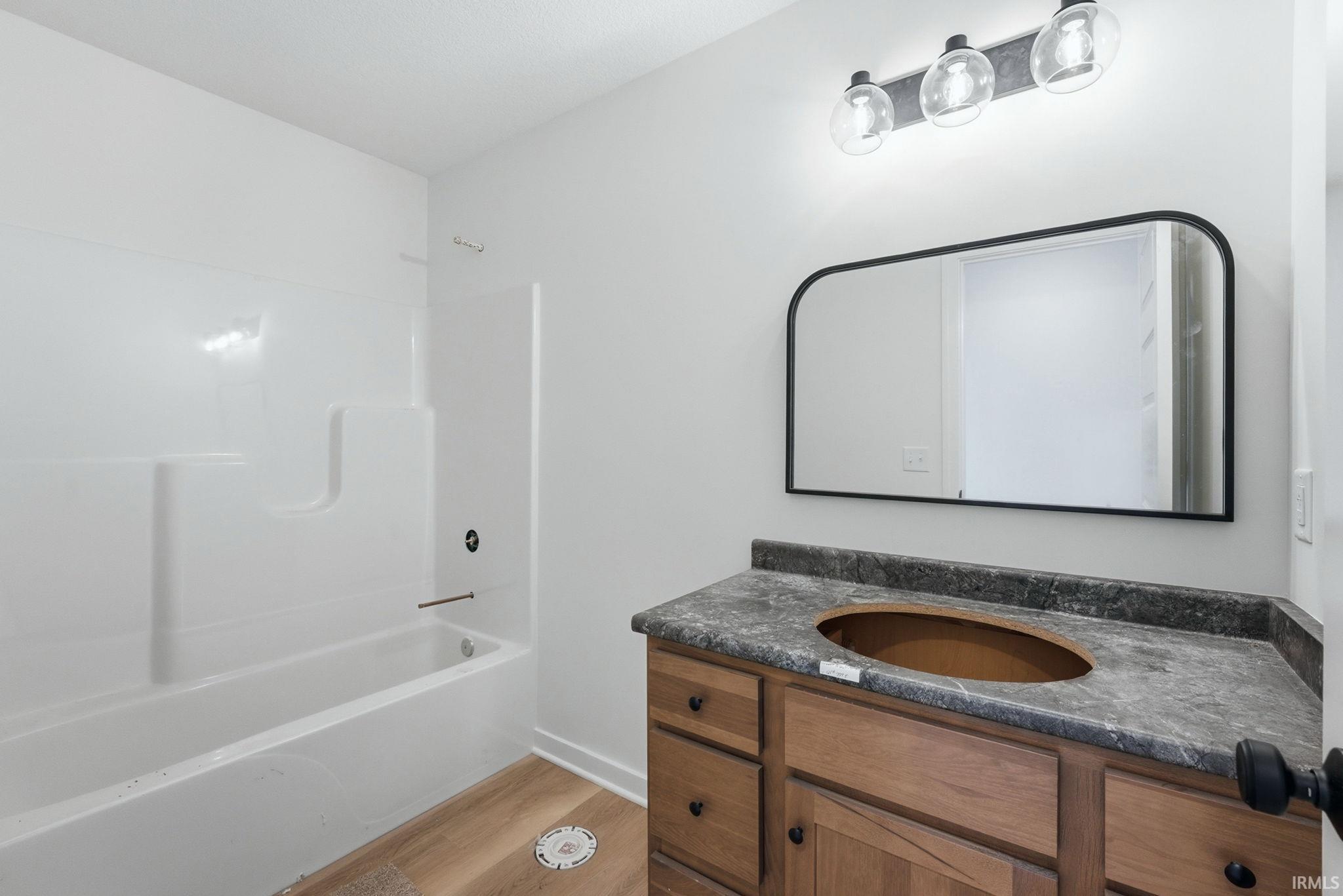 Full bathroom featuring vanity, shower / bath combination, and light wood-style floors
