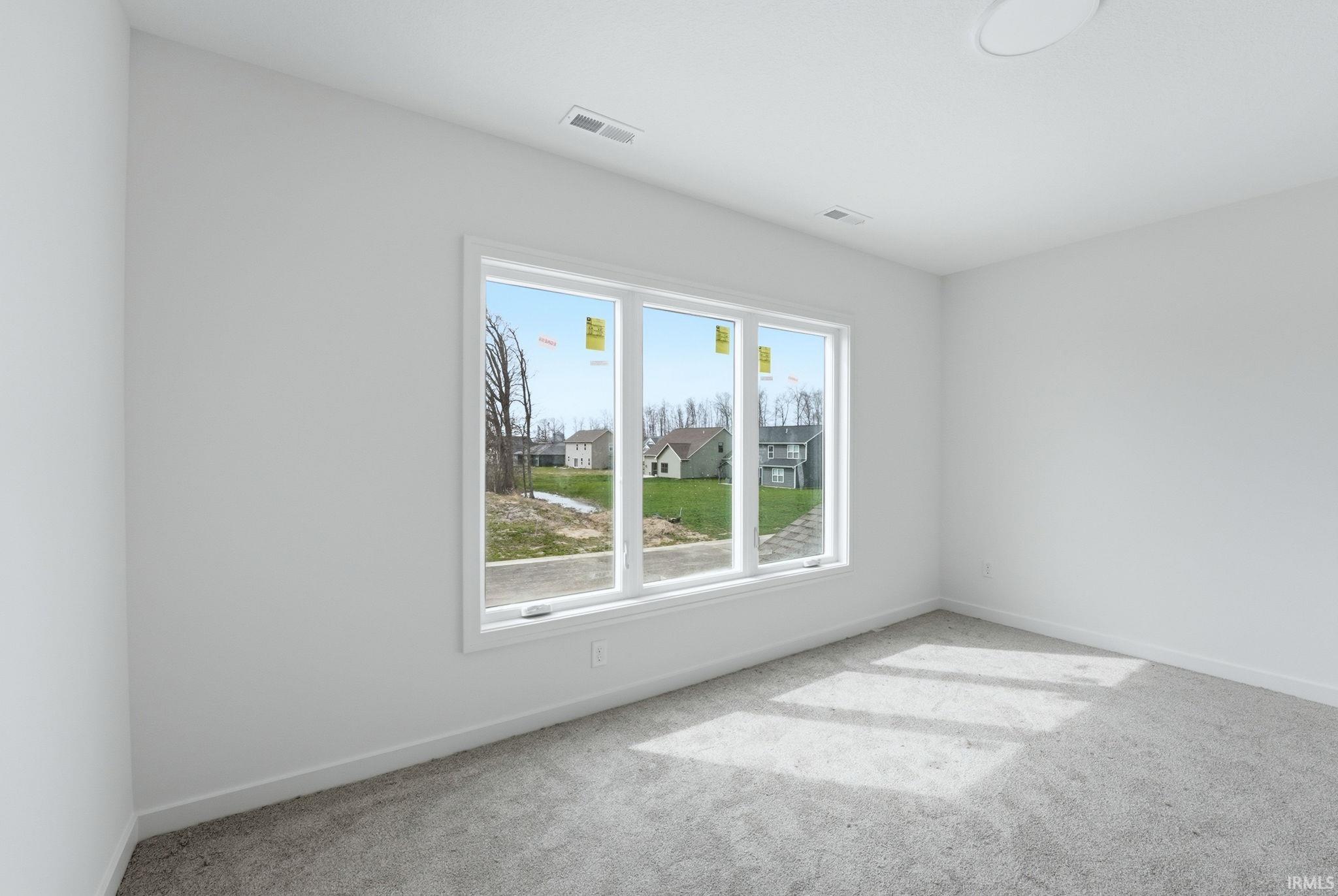 Spare room featuring light colored carpet and baseboards