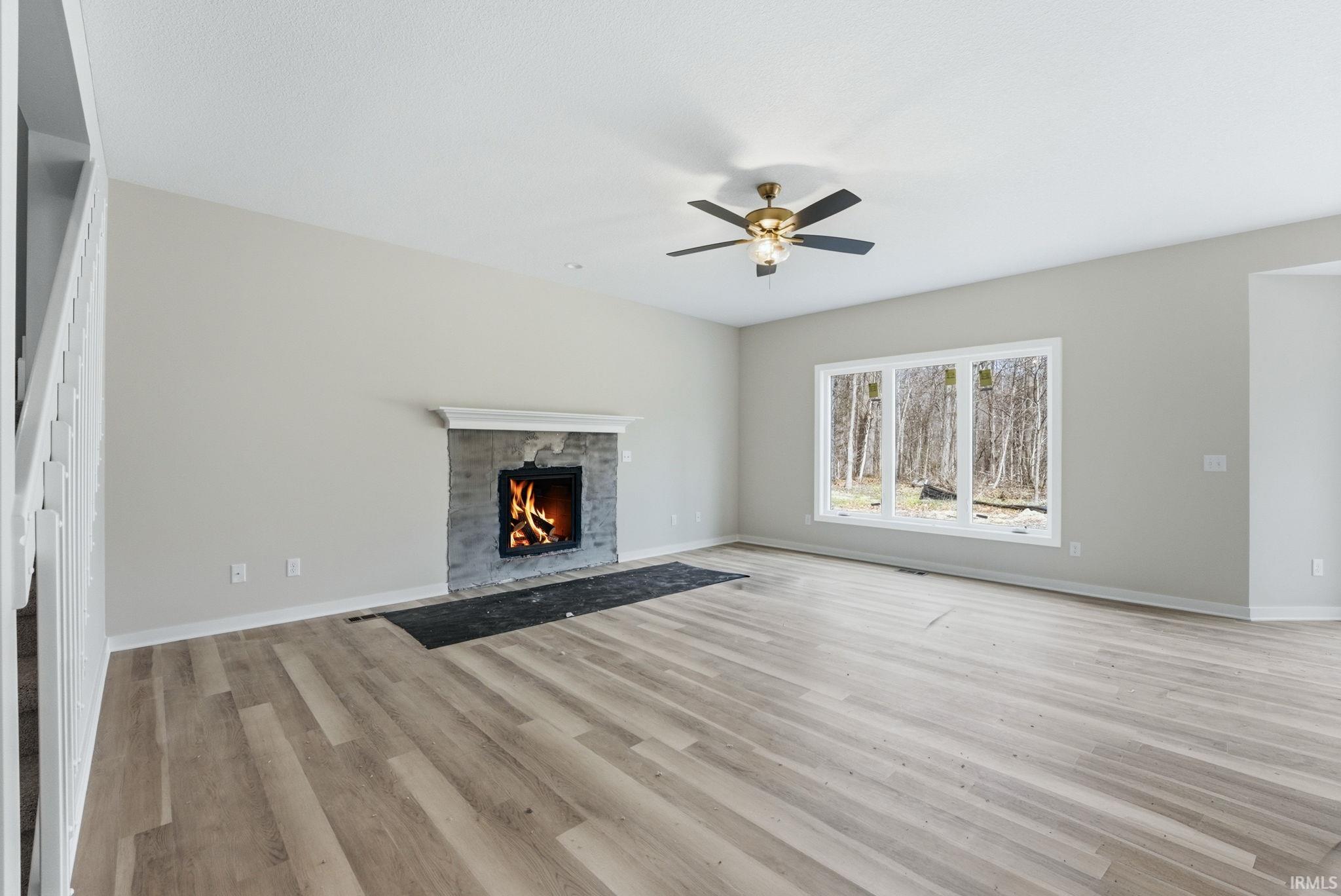Unfurnished living room with a fireplace, light wood-style flooring, and ceiling fan