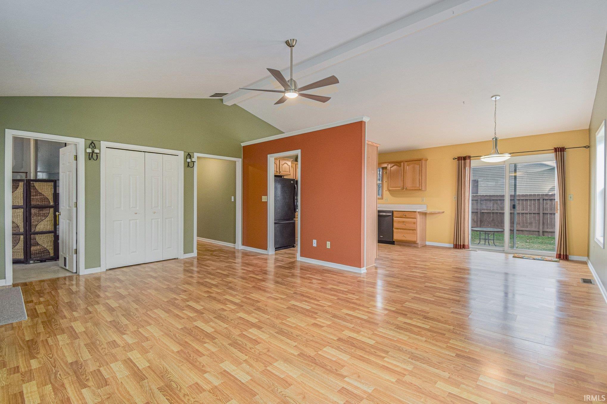 Unfurnished living room with ceiling fan, light wood-type flooring, and beam ceiling