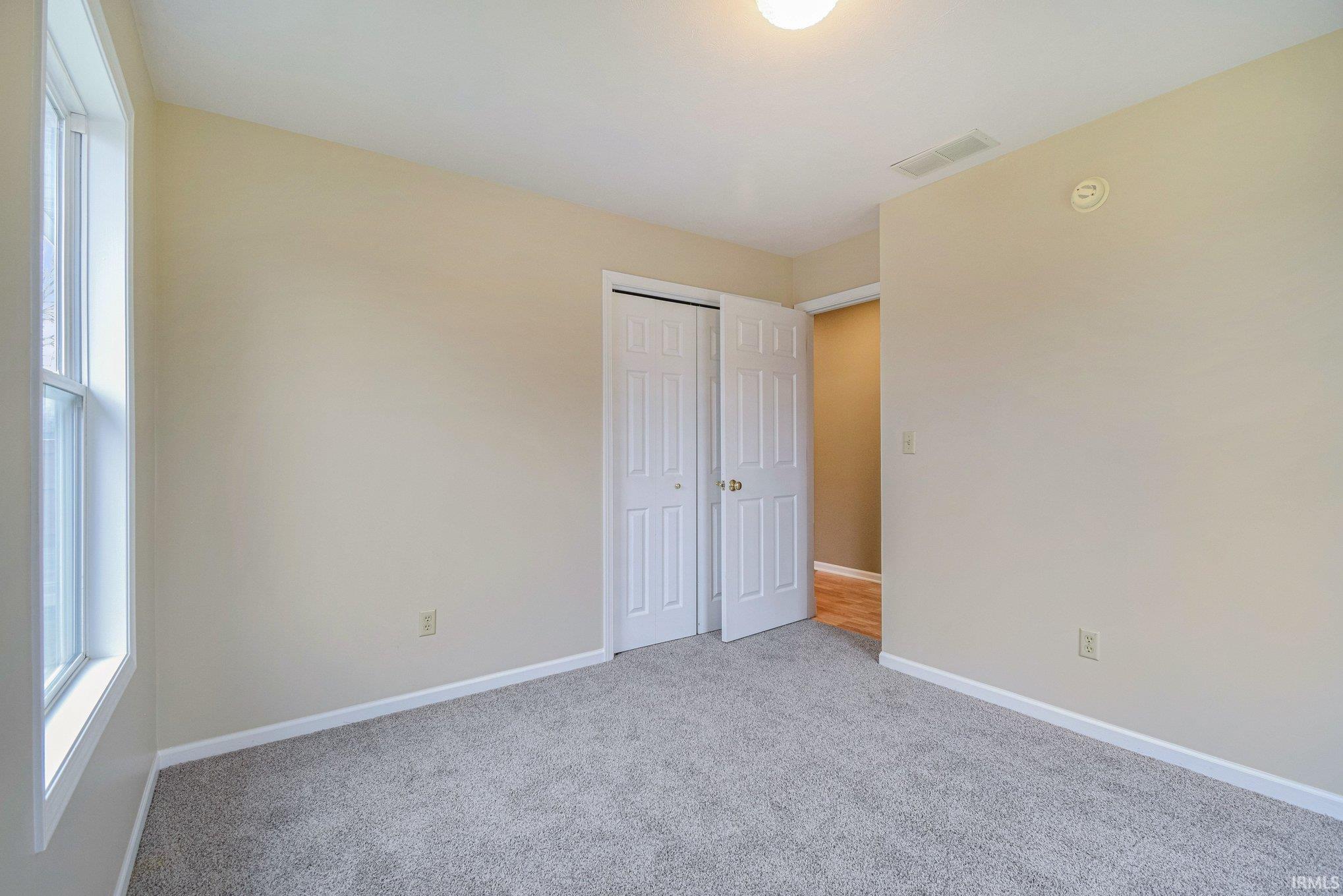 Unfurnished bedroom featuring light colored carpet and a closet