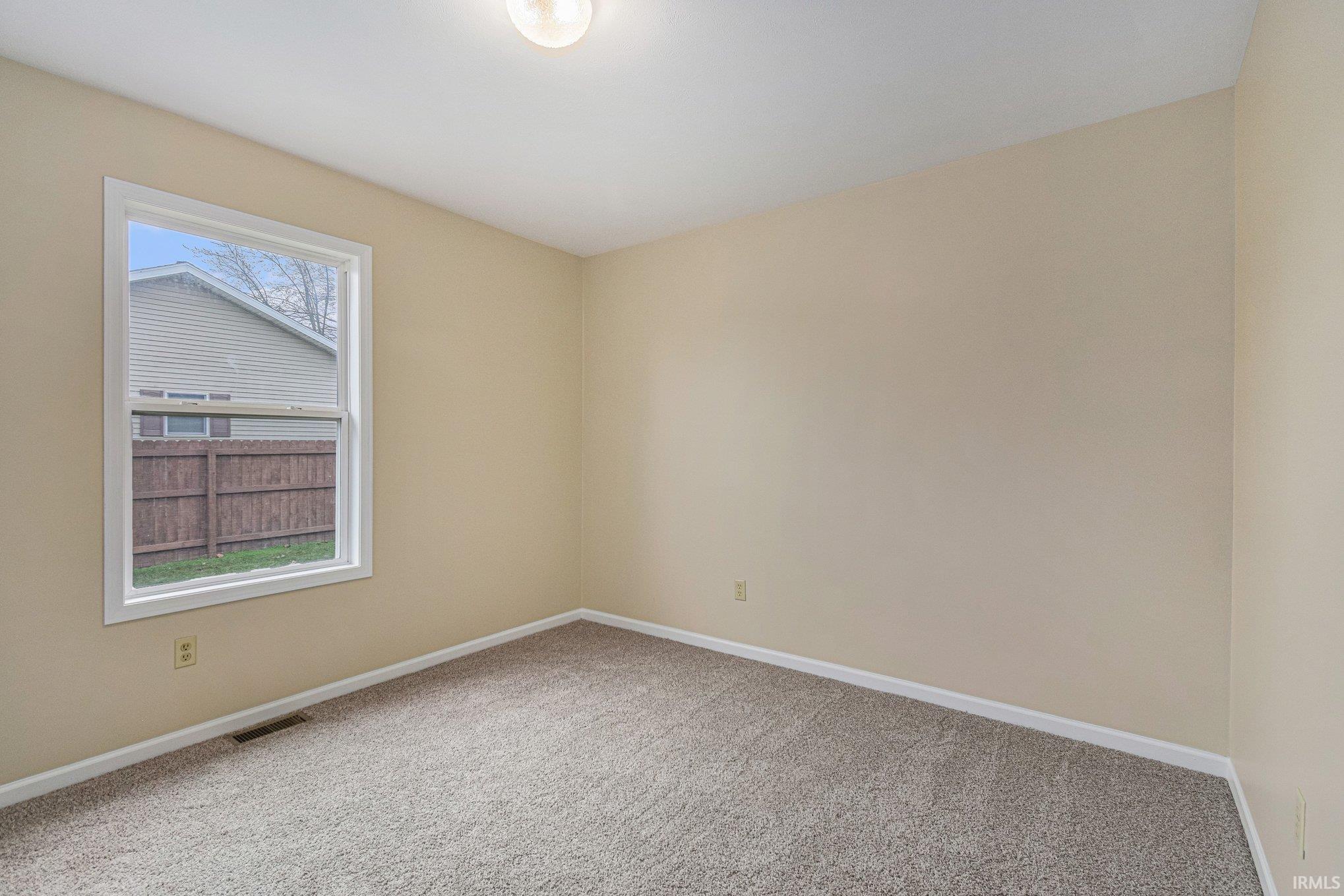 Spare room featuring baseboards and light carpet