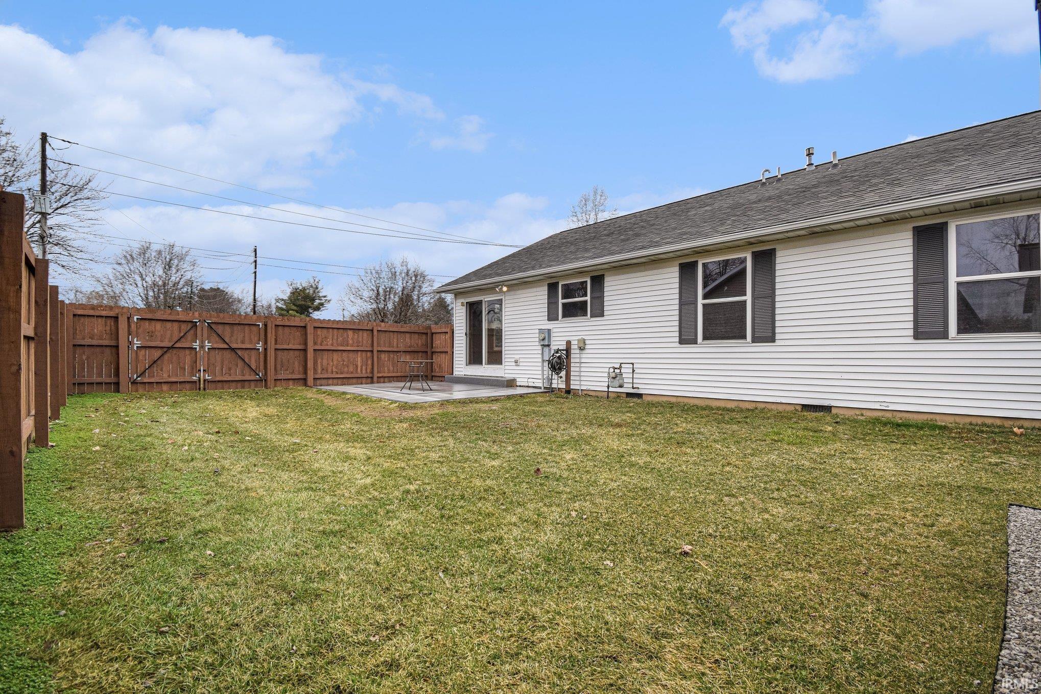 Rear view of house featuring a patio area, a fenced backyard, crawl space, roof with shingles, and a gate