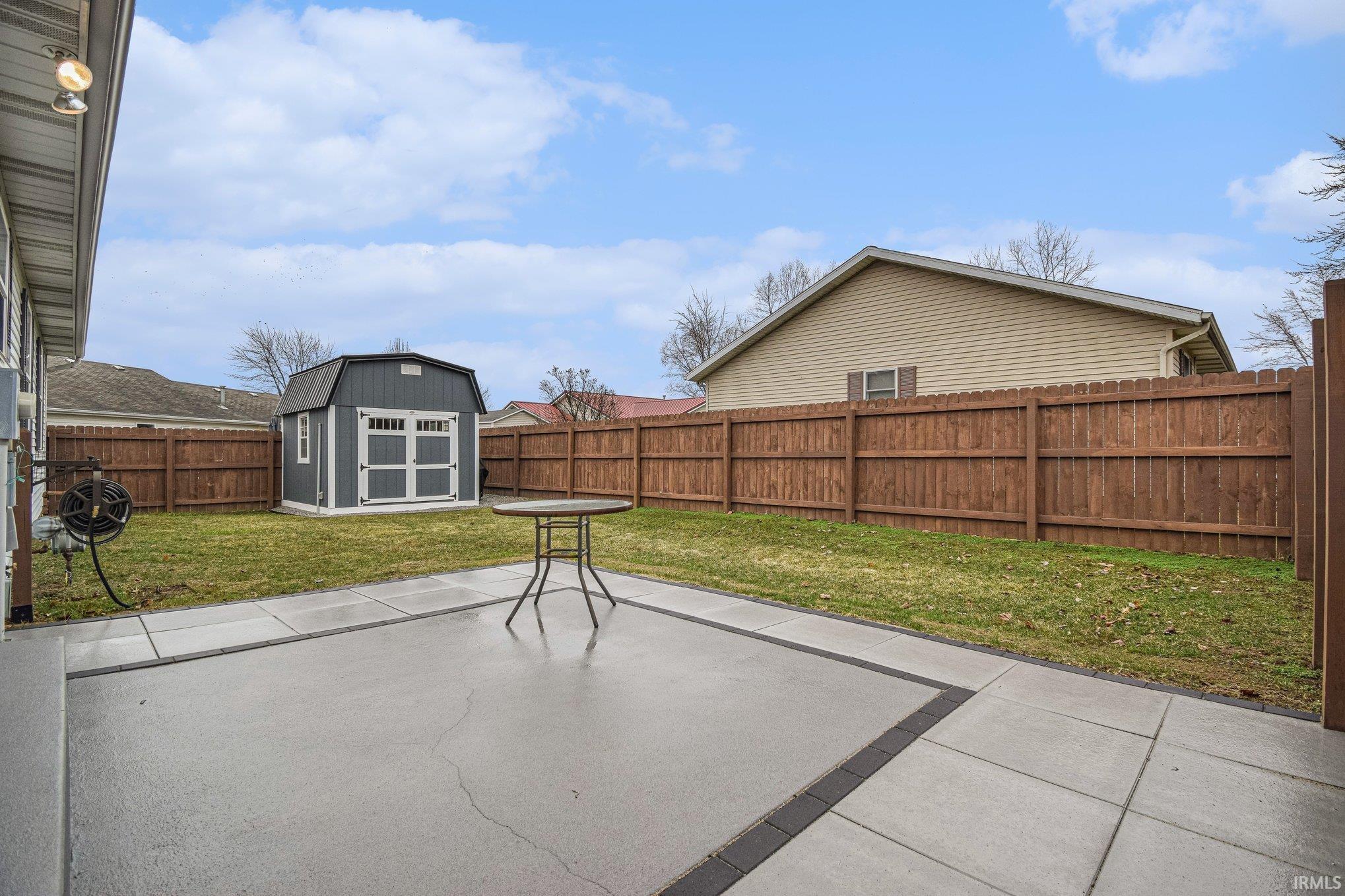 Fenced backyard with a storage shed and a patio area