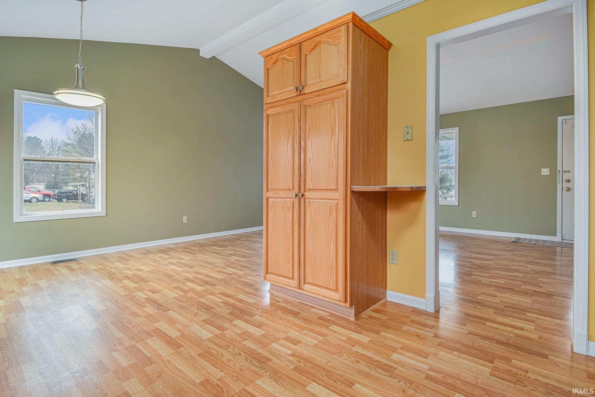 Kitchen with light wood-style flooring, lofted ceiling with beams, and hanging light fixtures