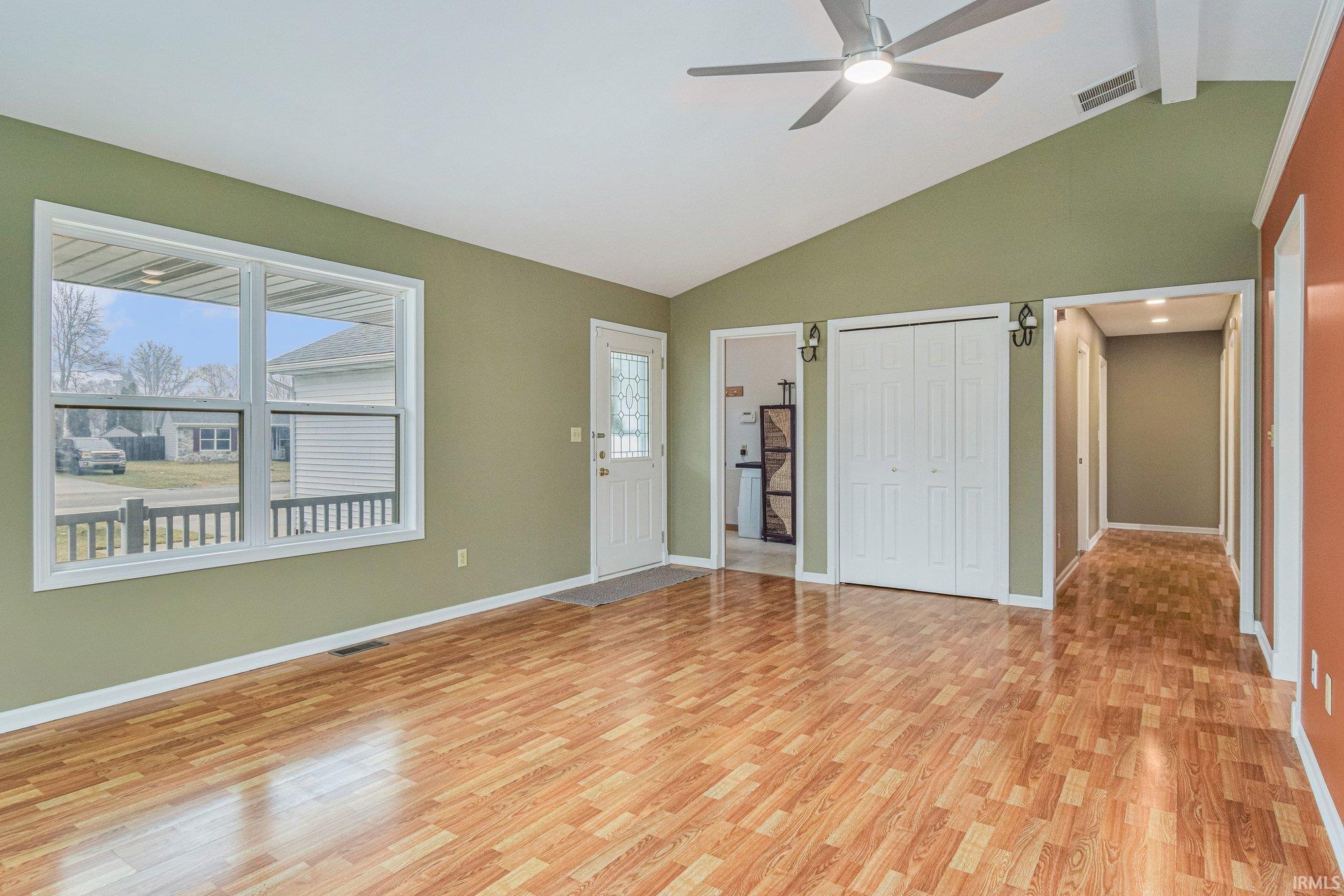 Unfurnished living room with vaulted ceiling, a ceiling fan, light wood-type flooring, and a barn door