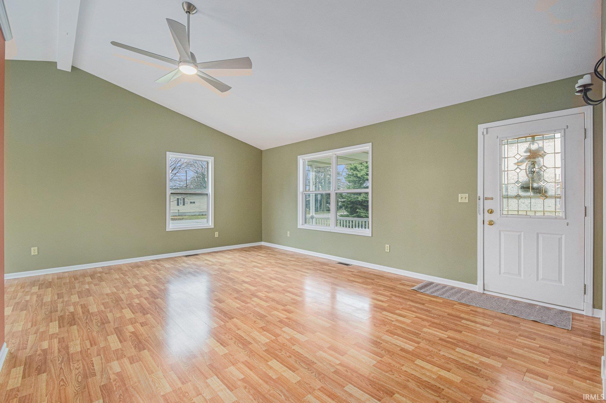 Unfurnished living room with light wood-type flooring, plenty of natural light, vaulted ceiling, and ceiling fan
