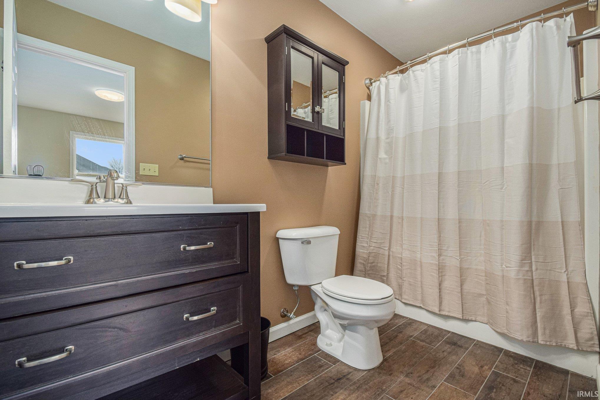 Full bath with wood tiled floors, vanity, and shower / tub combo with curtain