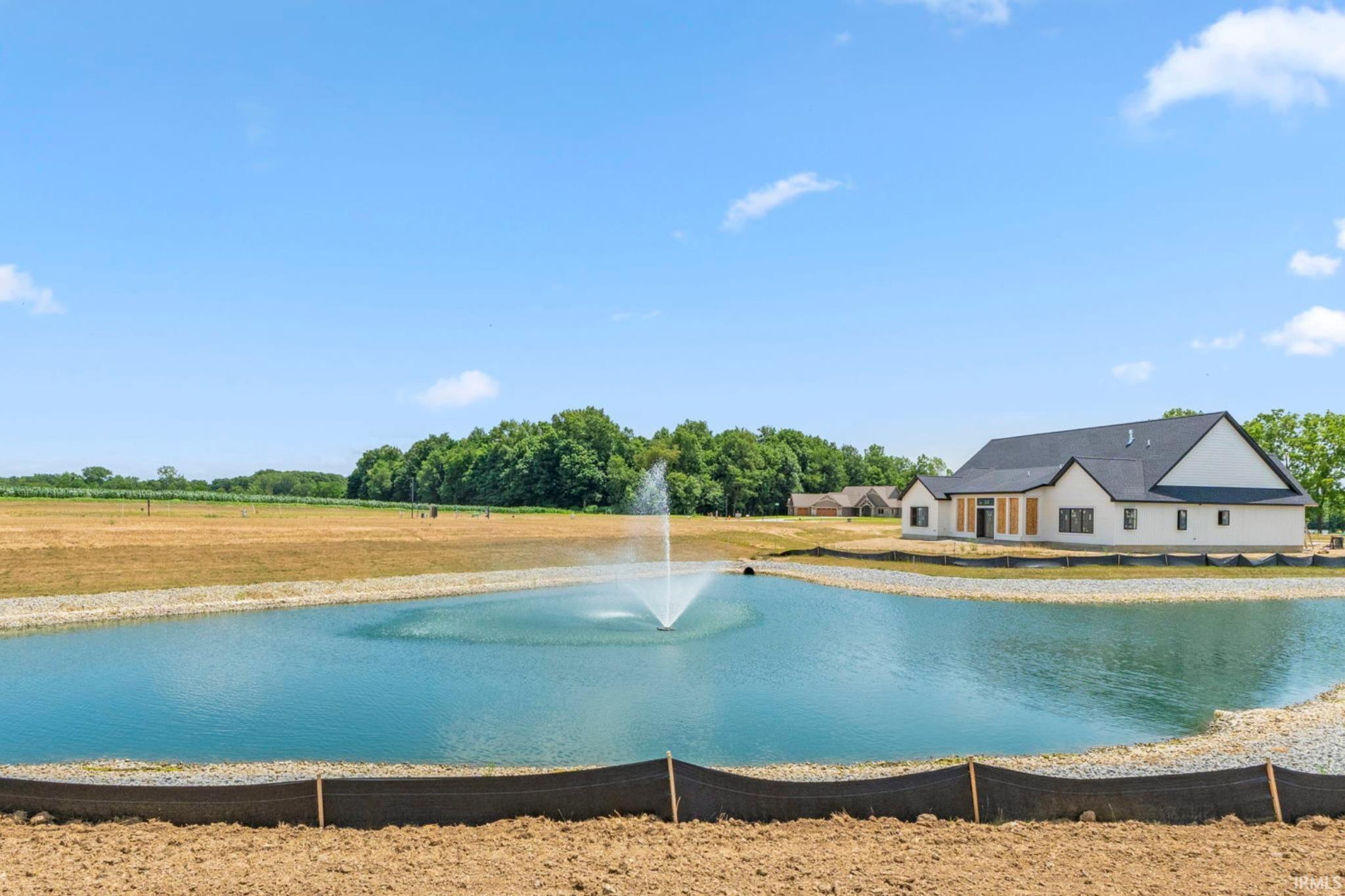 View of pool with a water view and a lawn