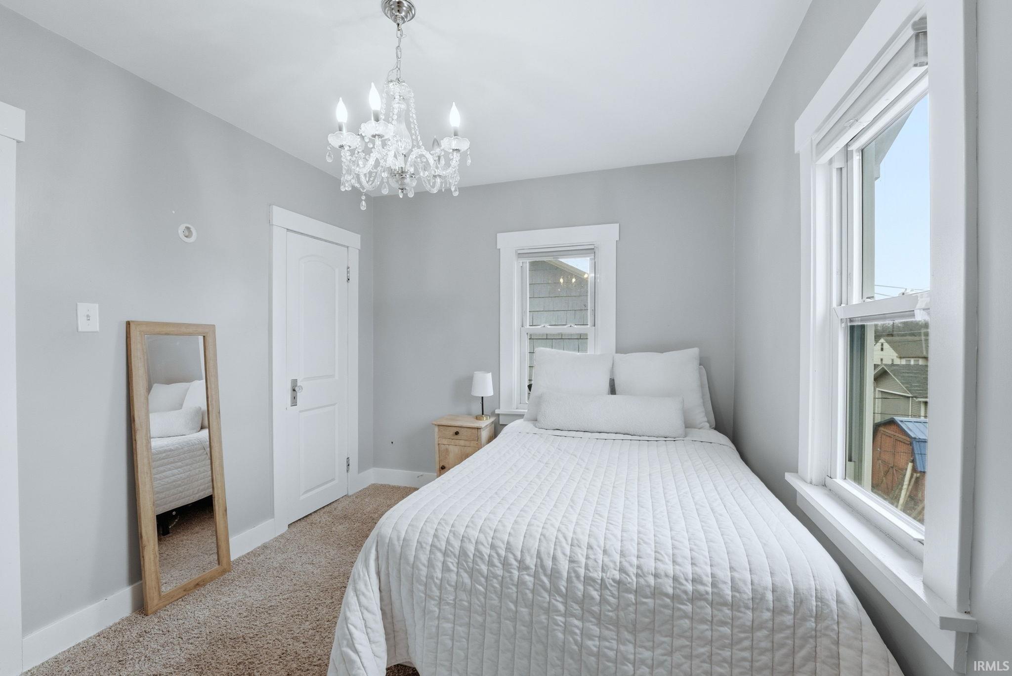 Bedroom with light carpet and hanging lights