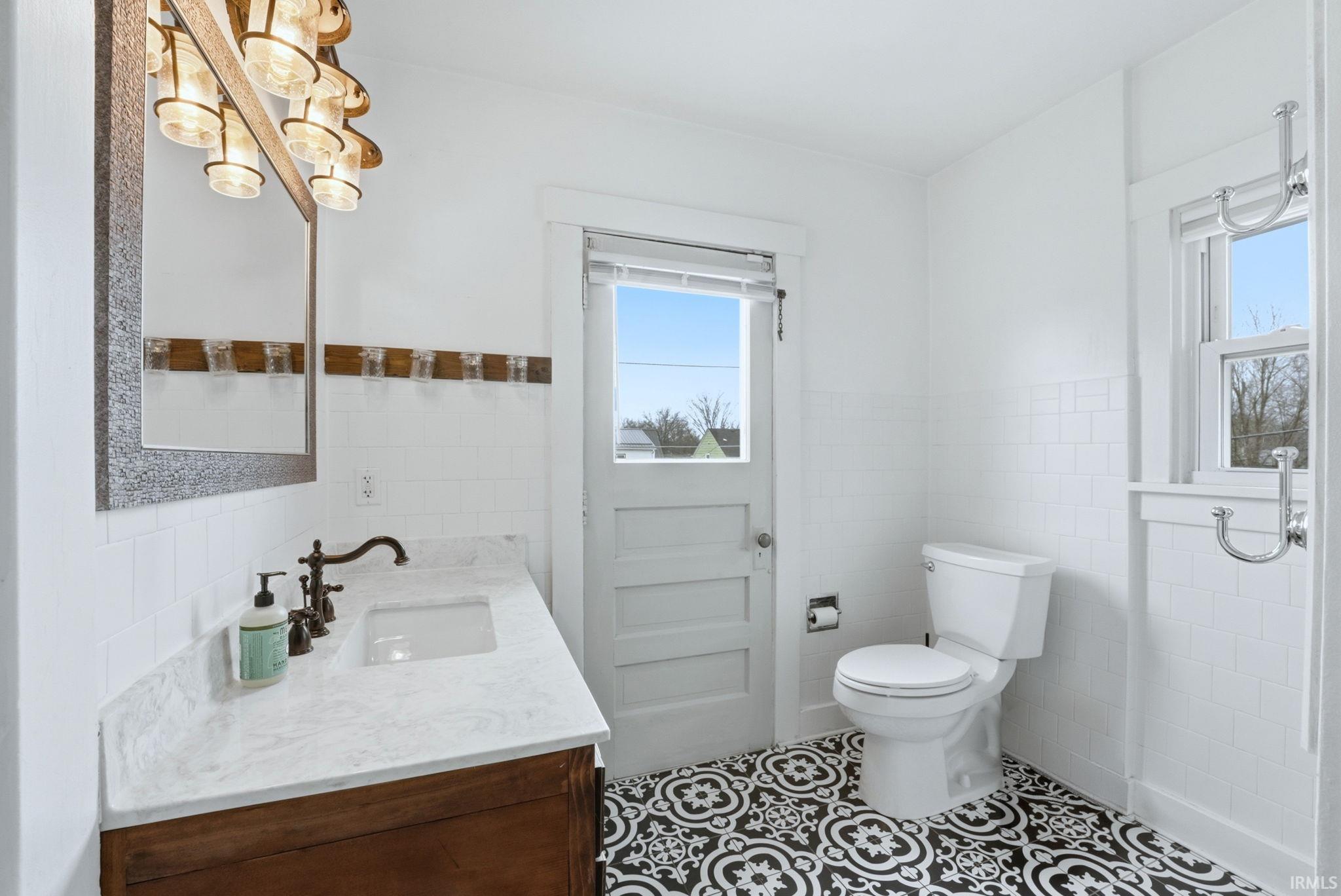 Bathroom featuring vanity, tile walls, light tile patterned flooring, and wainscoting