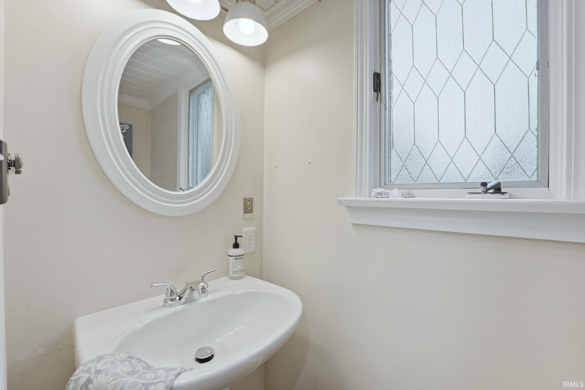 Bathroom with crown molding and a sink