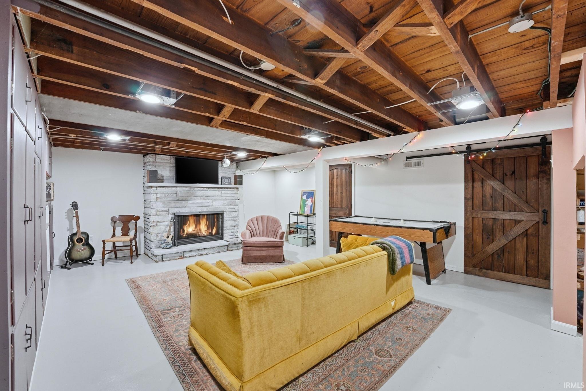 Living area featuring finished concrete floors, a barn door, and a stone fireplace