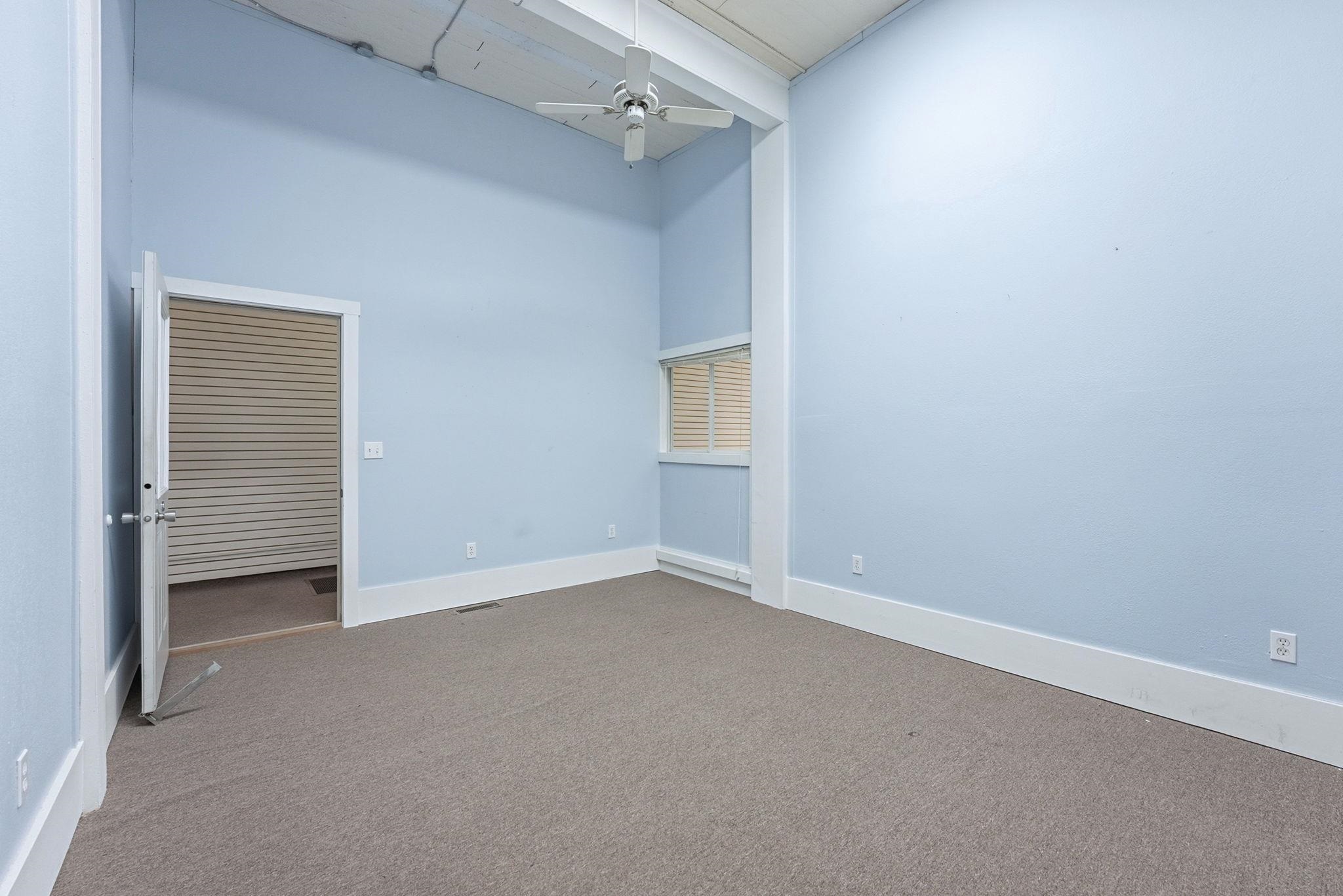 Carpeted empty room with a ceiling fan and a high ceiling