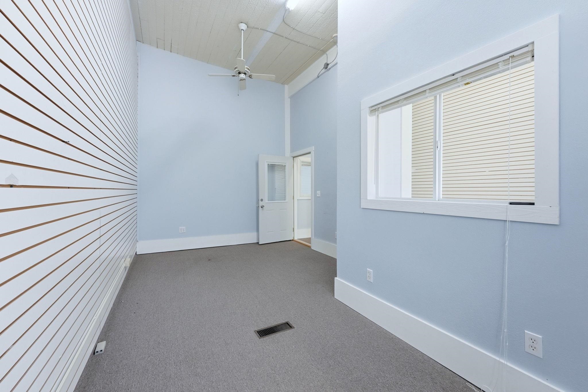Carpeted spare room with a ceiling fan and a high ceiling