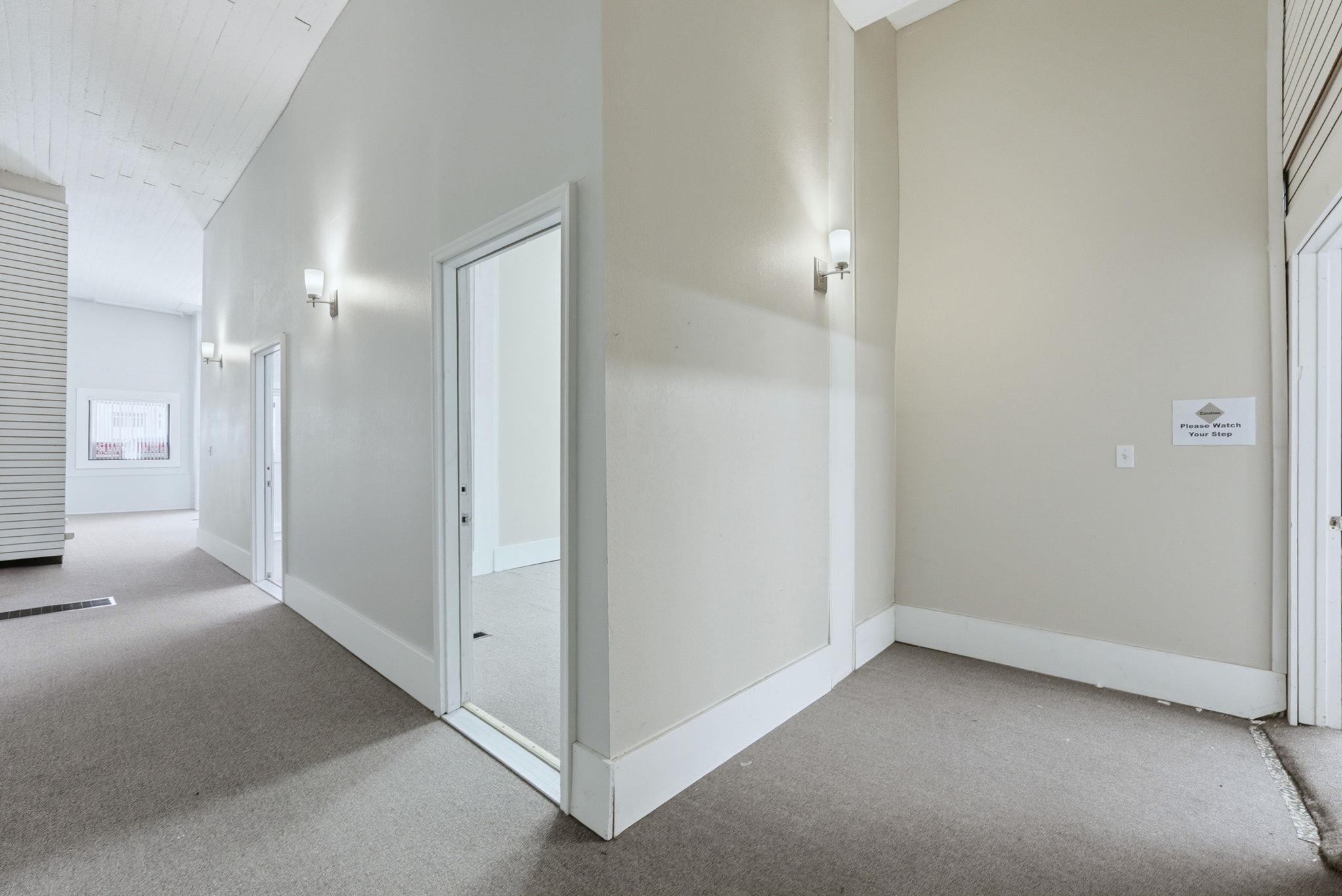 Corridor featuring light carpet and a high ceiling