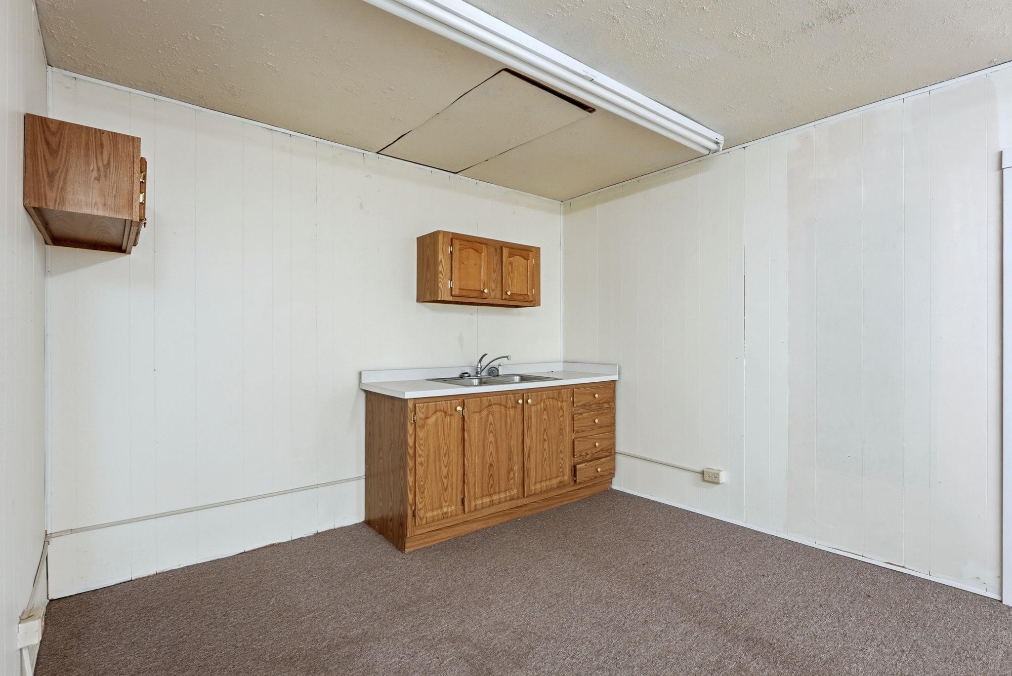 Bar area featuring light countertops, wood finish cabinets, a textured ceiling, dark carpet, and wooden walls