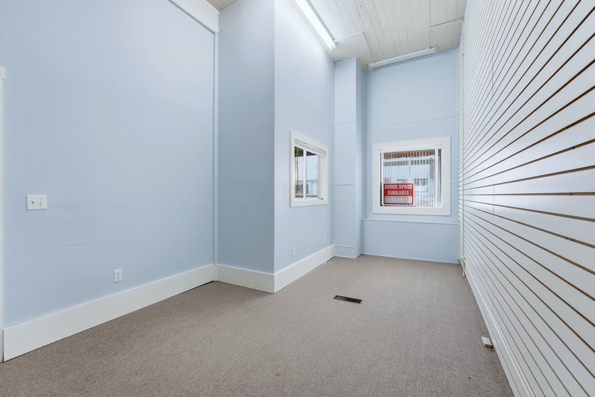 Empty room with light colored carpet and a high ceiling