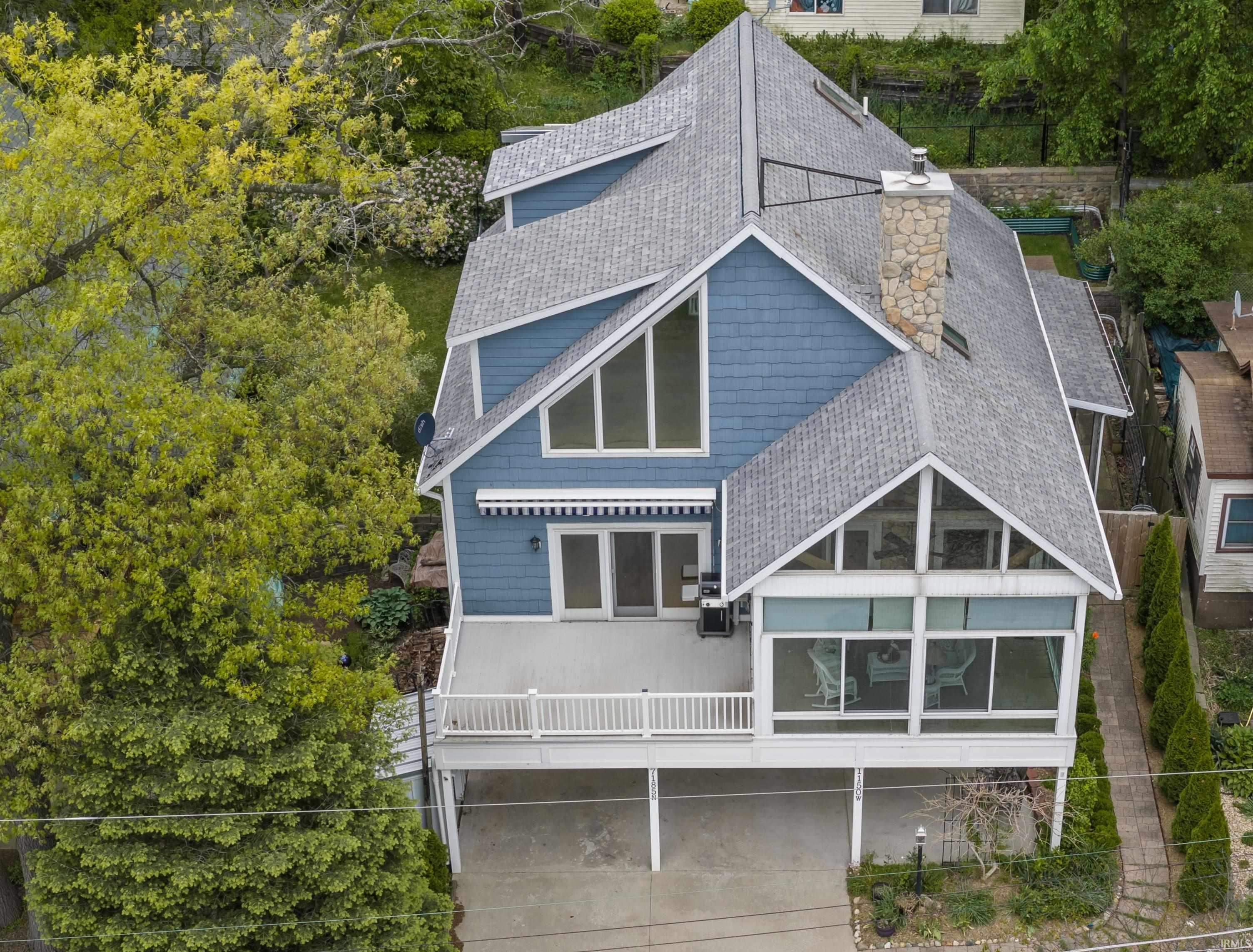 Contemporary multi-level residence featuring blue siding and a prominent stone chimney