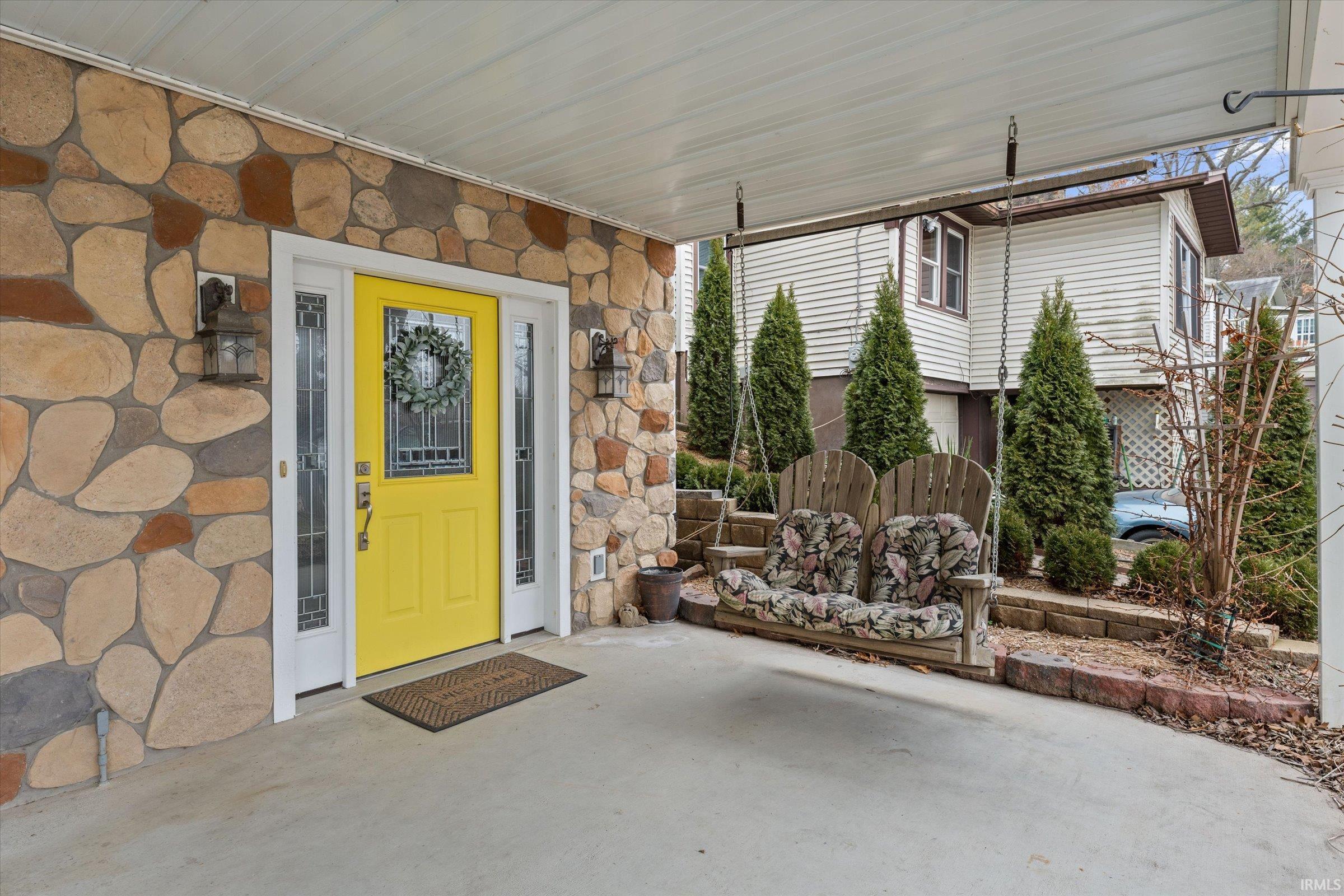 Entrance to property with stone siding and a patio area