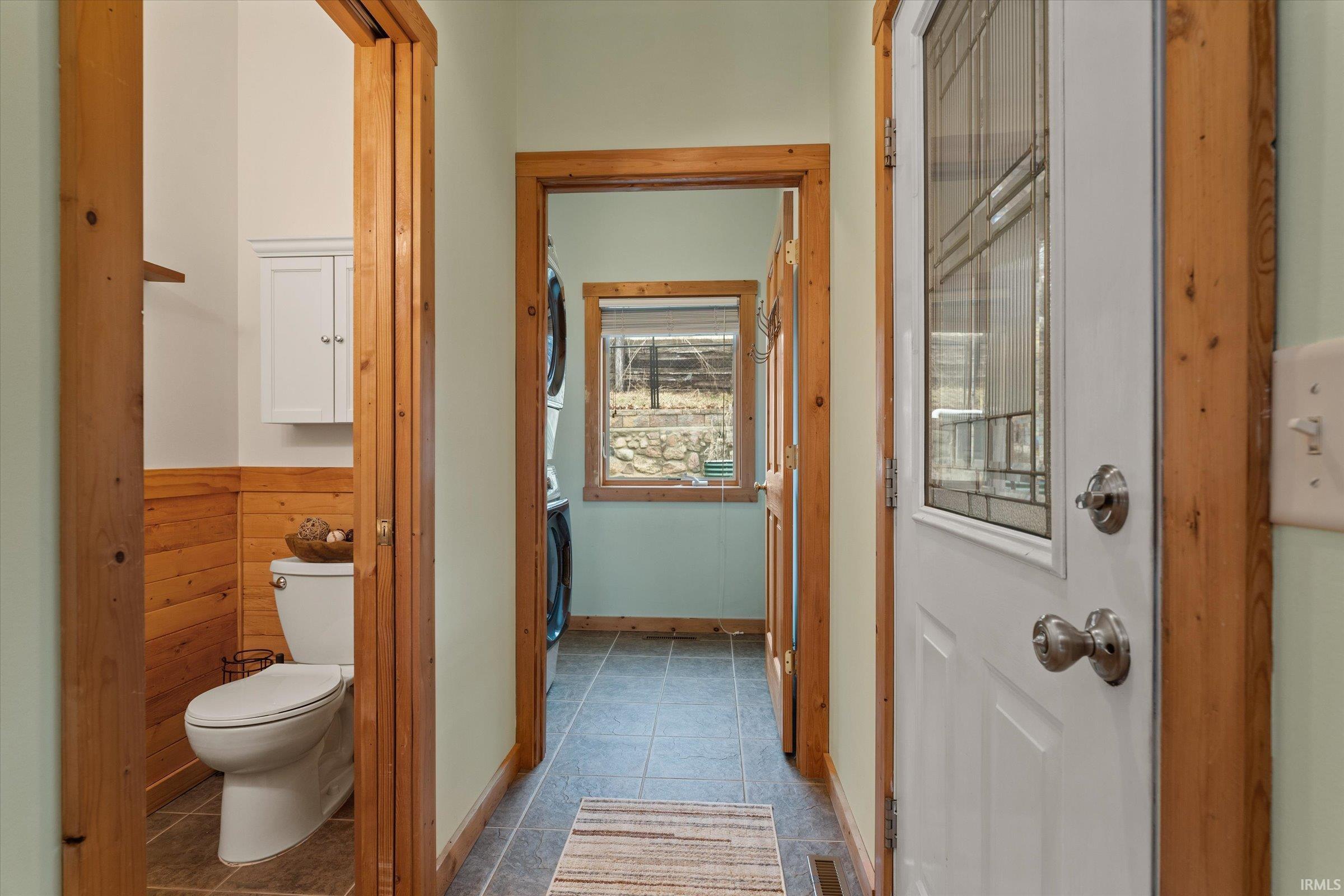 Bathroom featuring toilet and stacked washer / drying machine