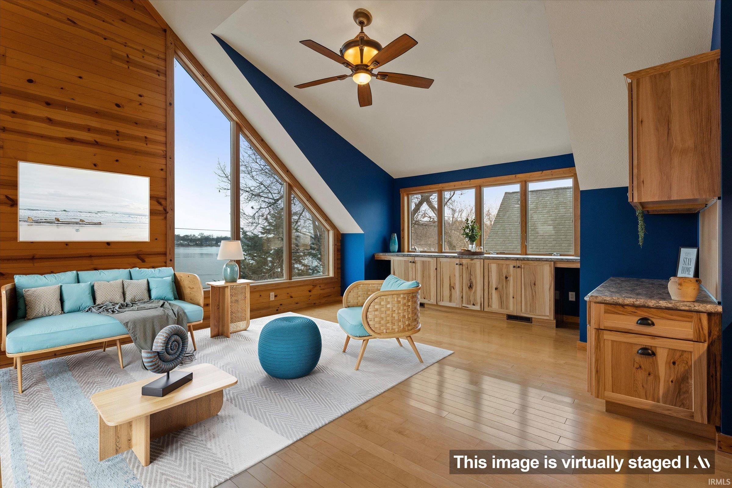 Living area with light wood finished floors, ceiling fan, vaulted ceiling, and wooden walls