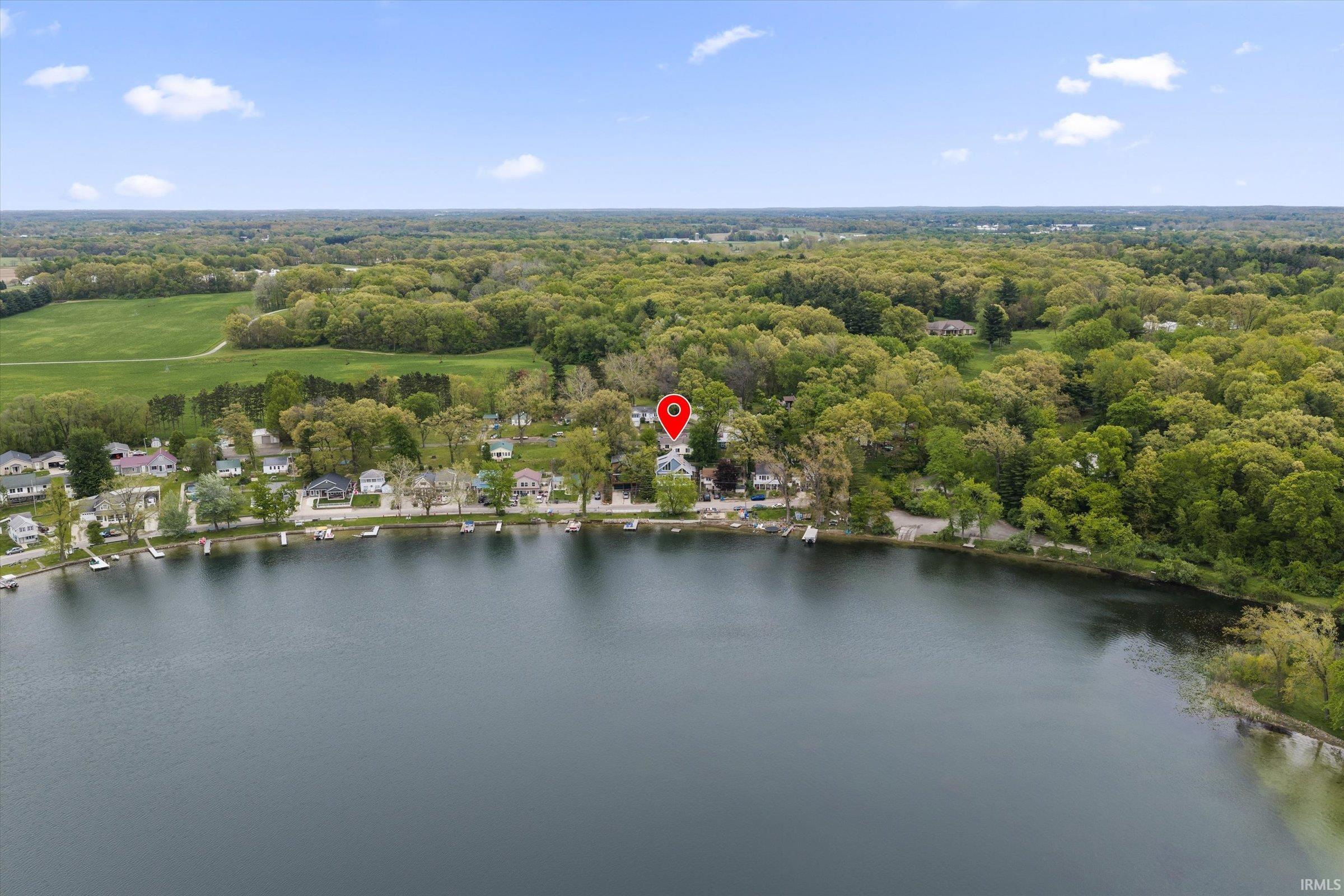Waterfront property positioned along a lake, surrounded by mature trees and residential landscaping