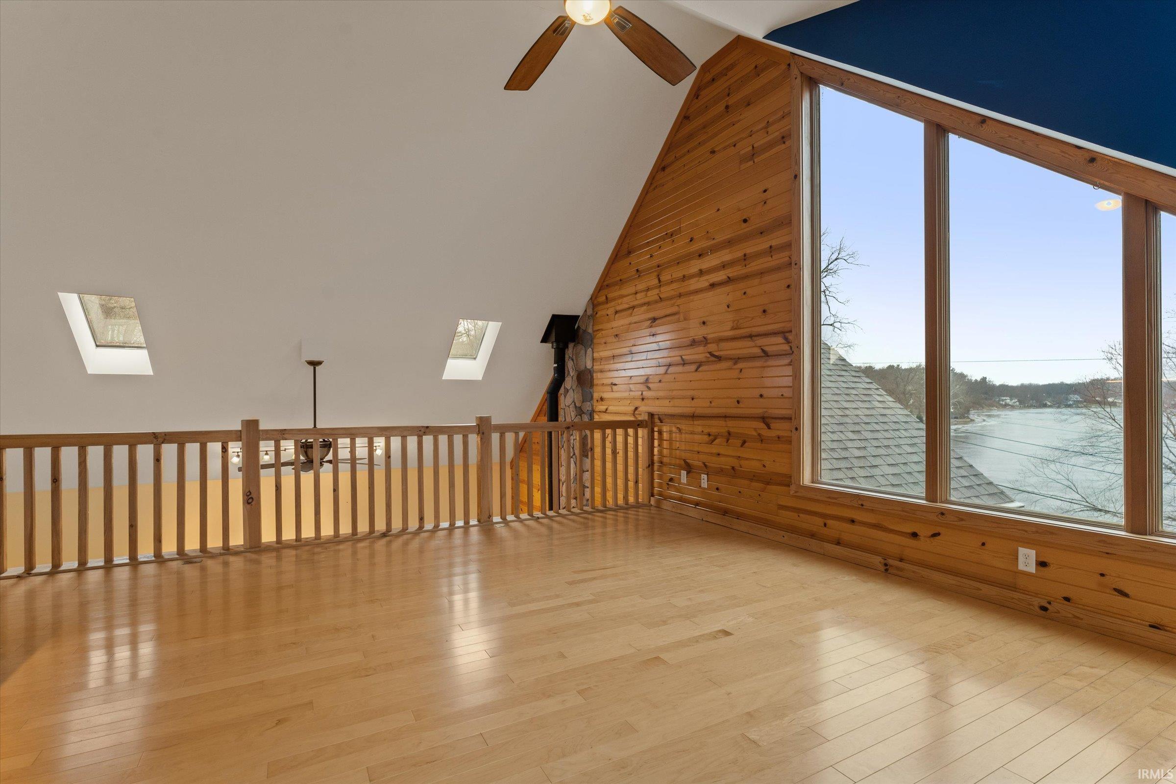 Bonus room with ceiling fan, wooden walls, wood-type flooring, lofted ceiling, and a skylight