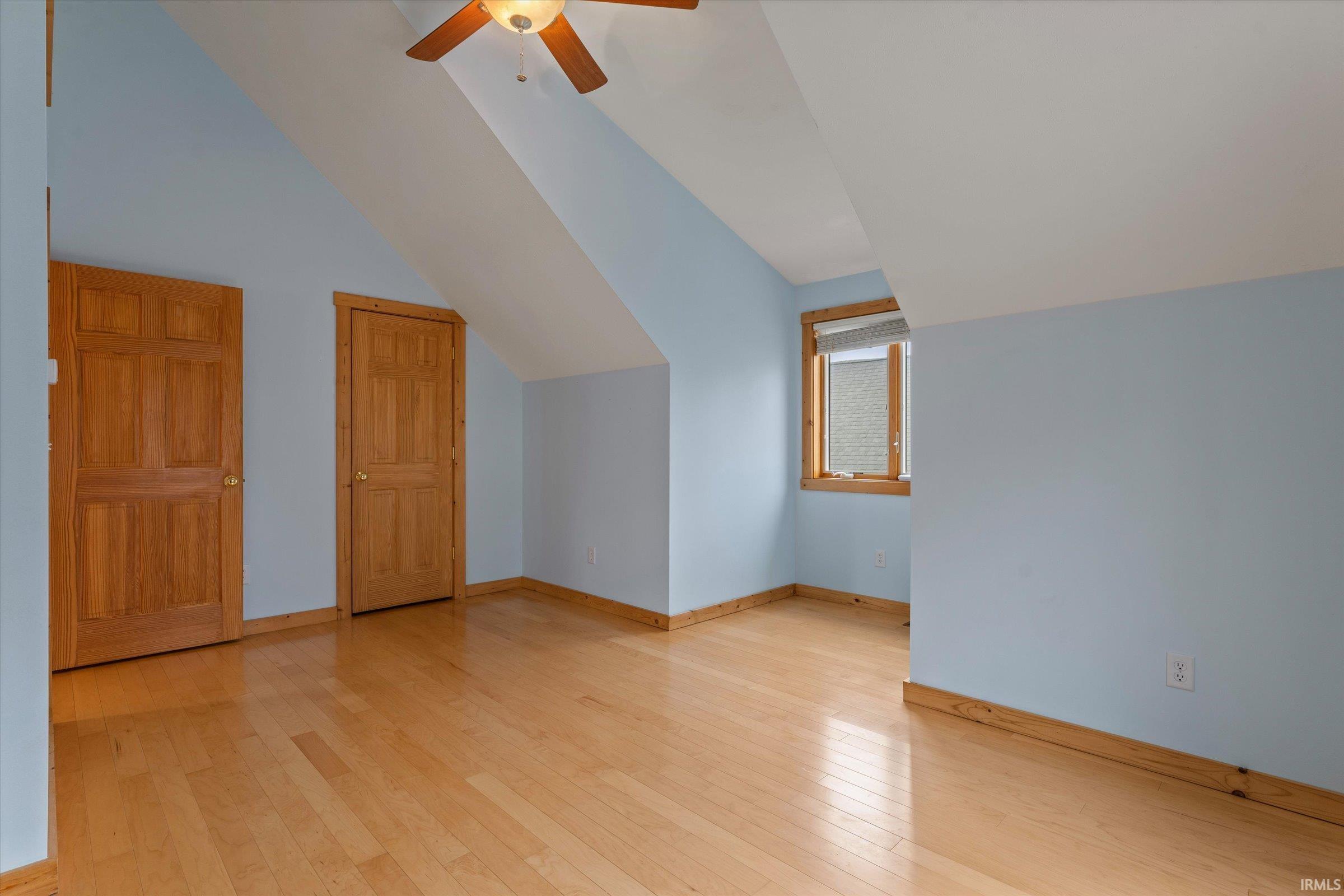 Additional living space with light wood finished floors, ceiling fan, and vaulted ceiling