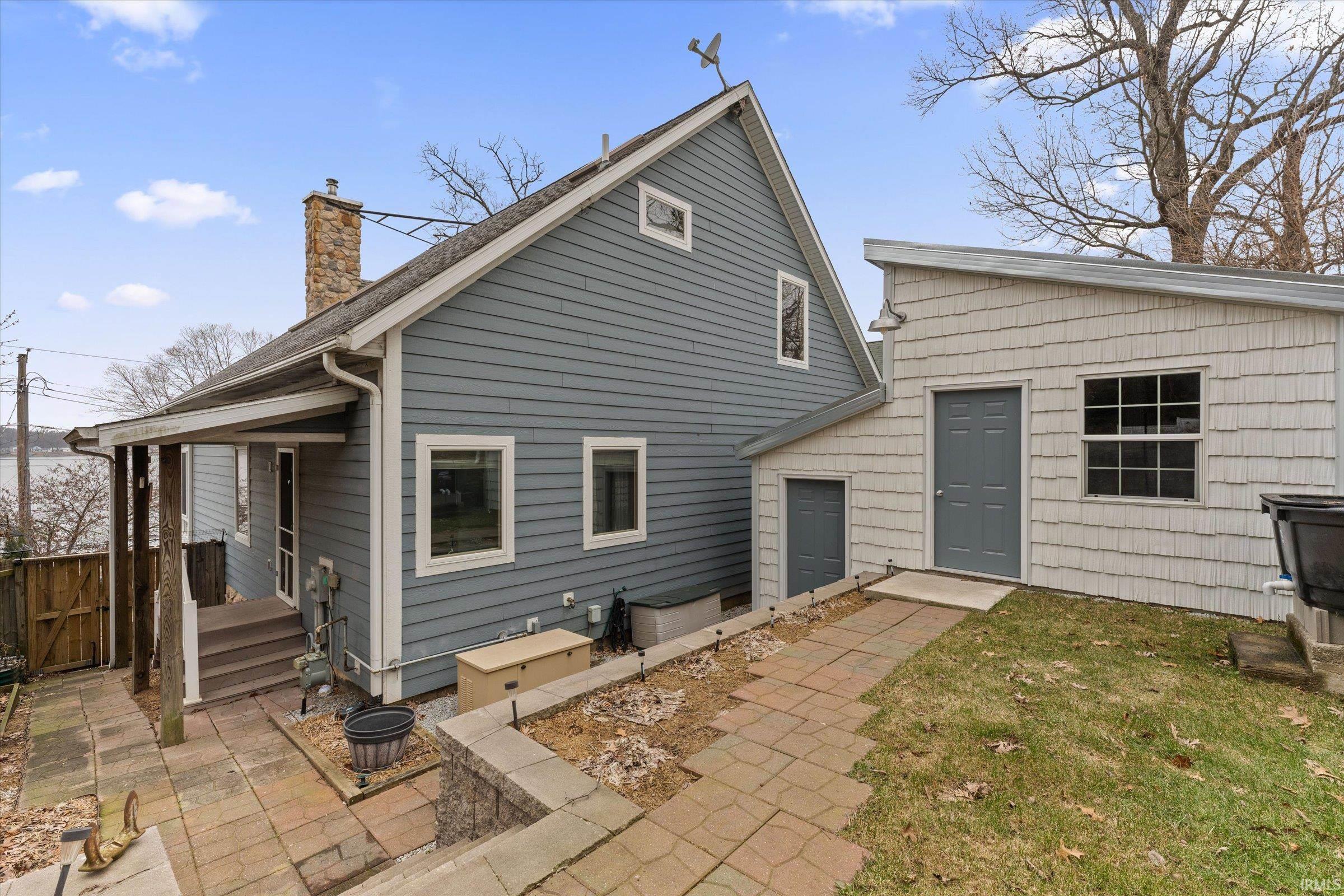 Back of house featuring a chimney, a lawn, a gate, and a patio area